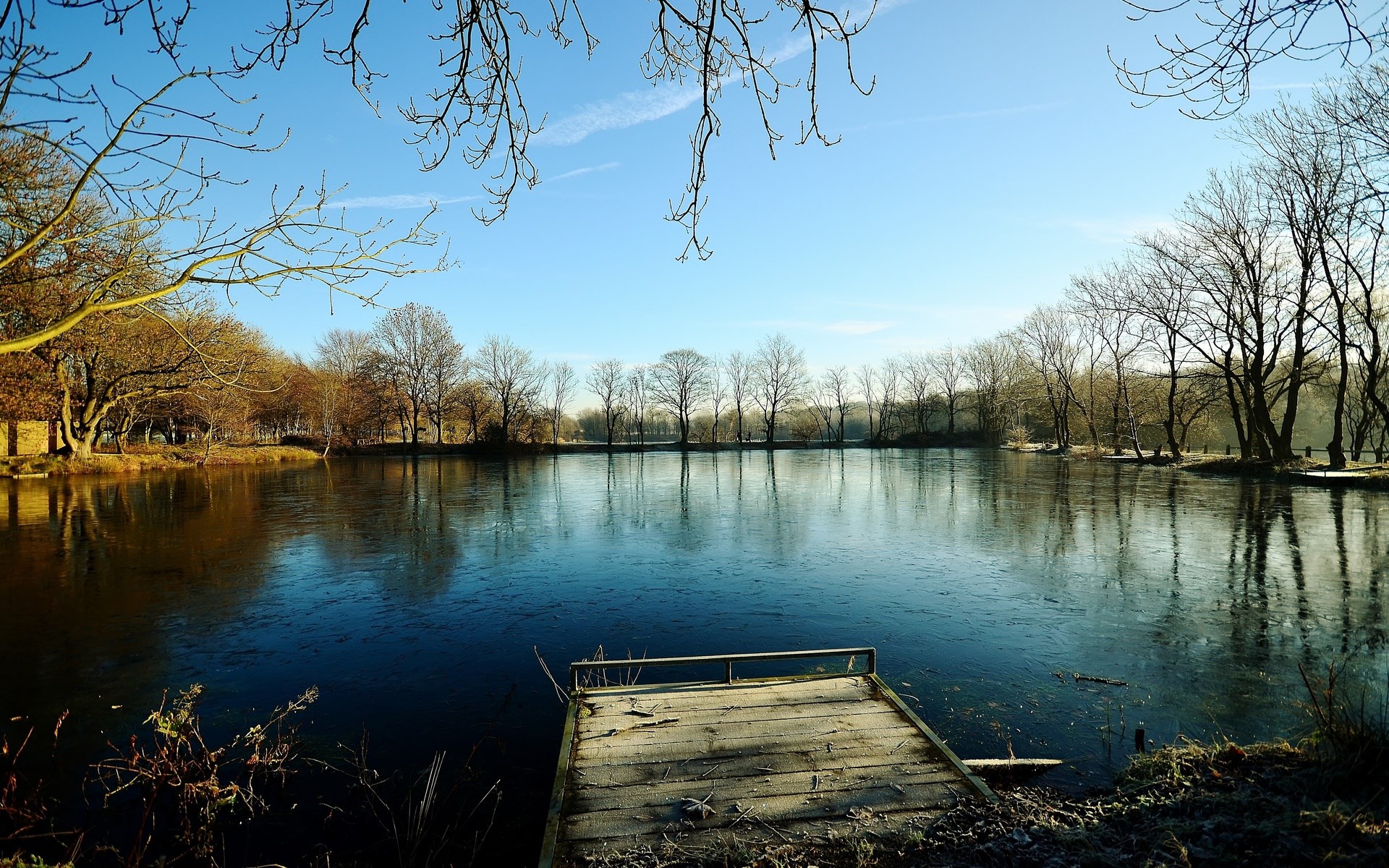 Wooden dock on a frozen lake with bare trees HD Wallpaper