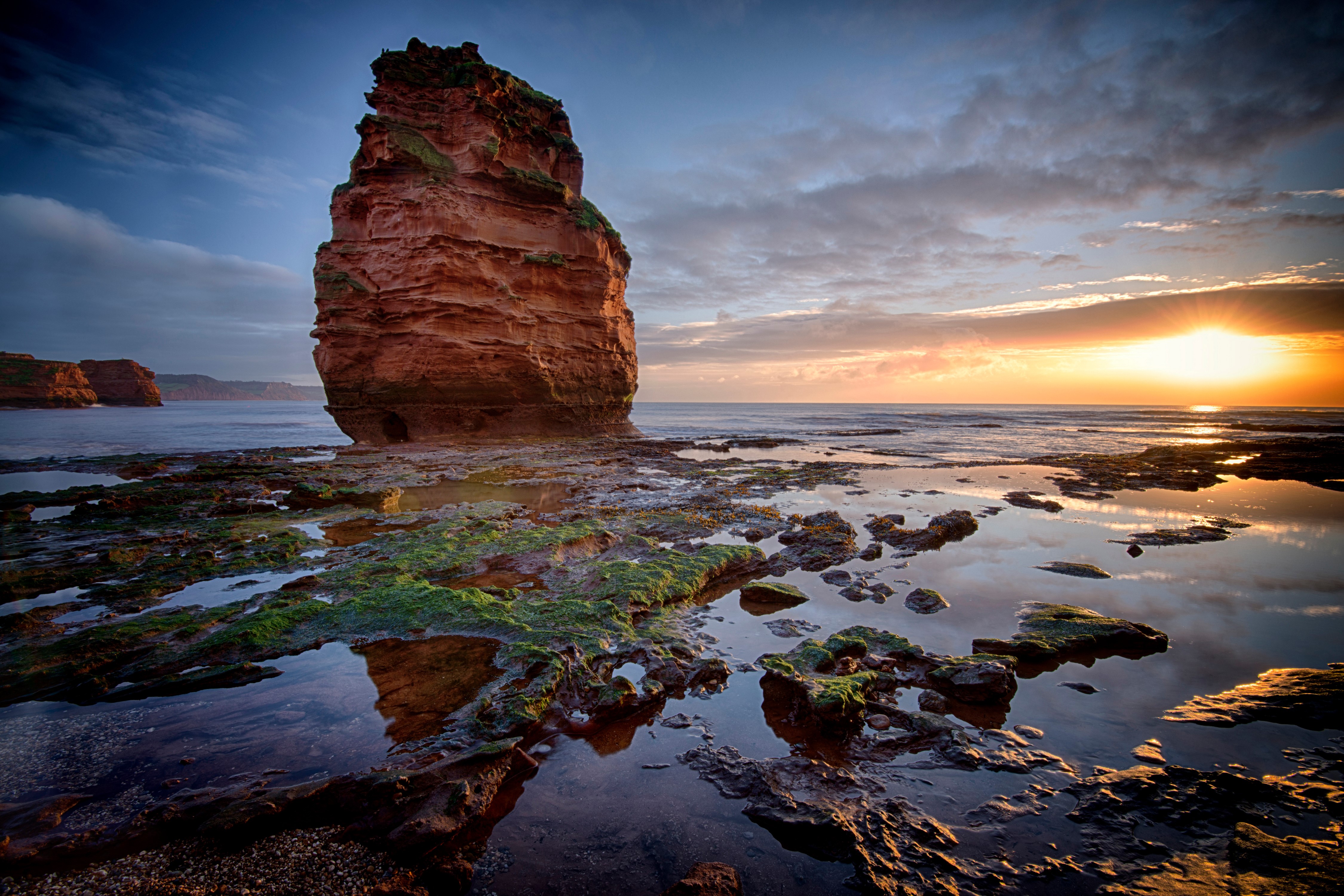 Red rock formation on the coast of Devon, England at sunset HD Wallpaper
