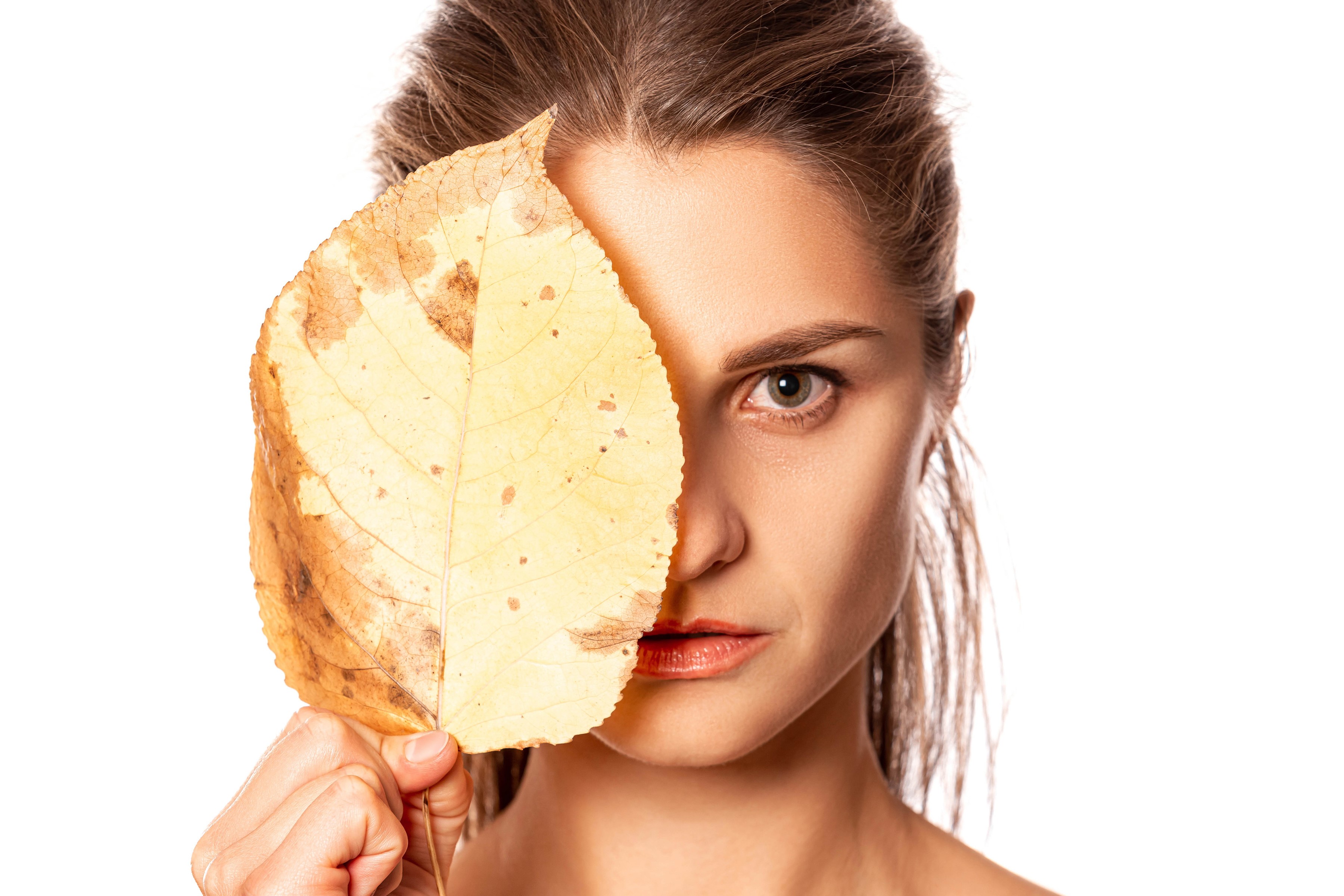 Woman holding a yellow leaf over her face HD Wallpaper