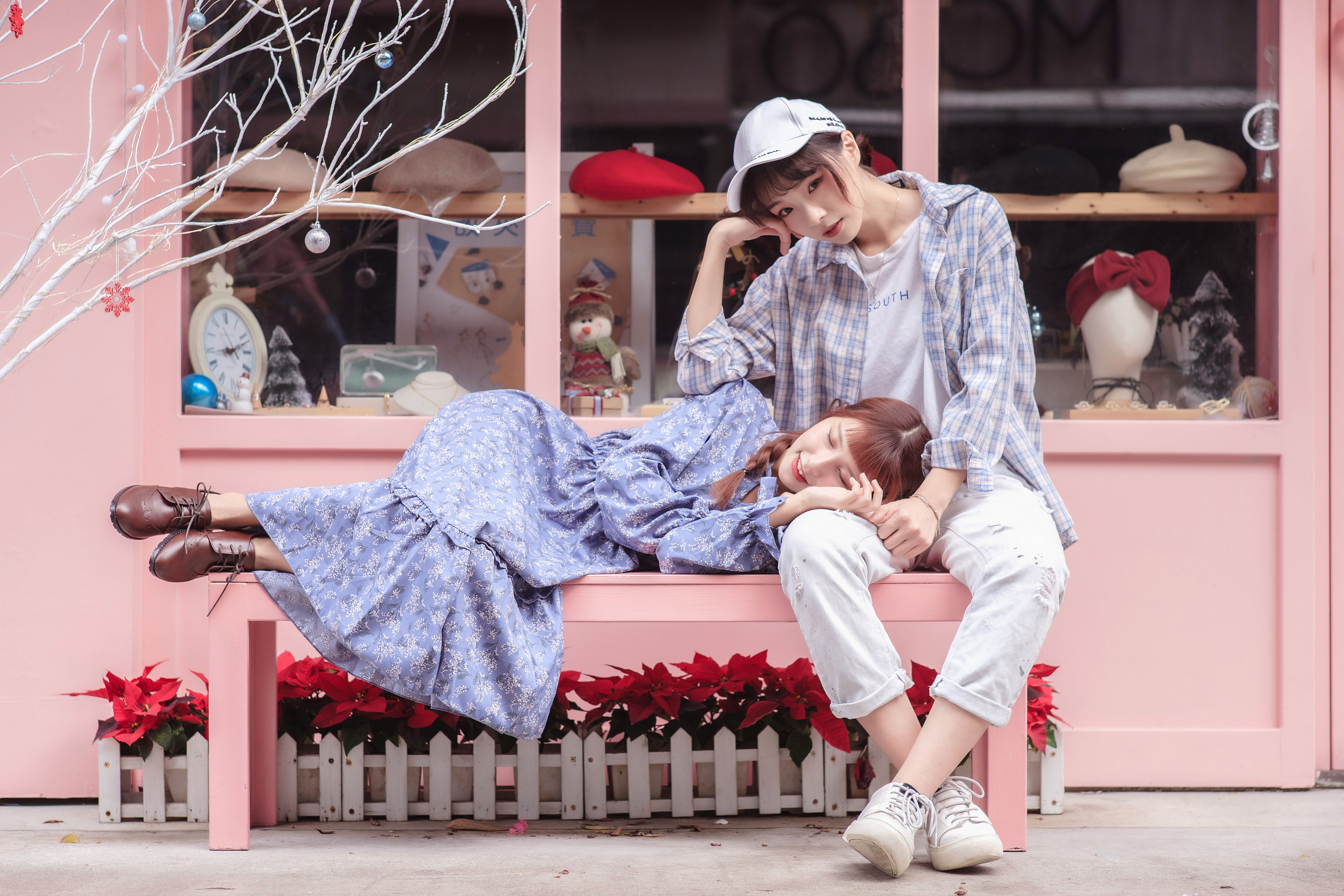 Two Asian women sitting and lying on a pink bench HD Wallpaper