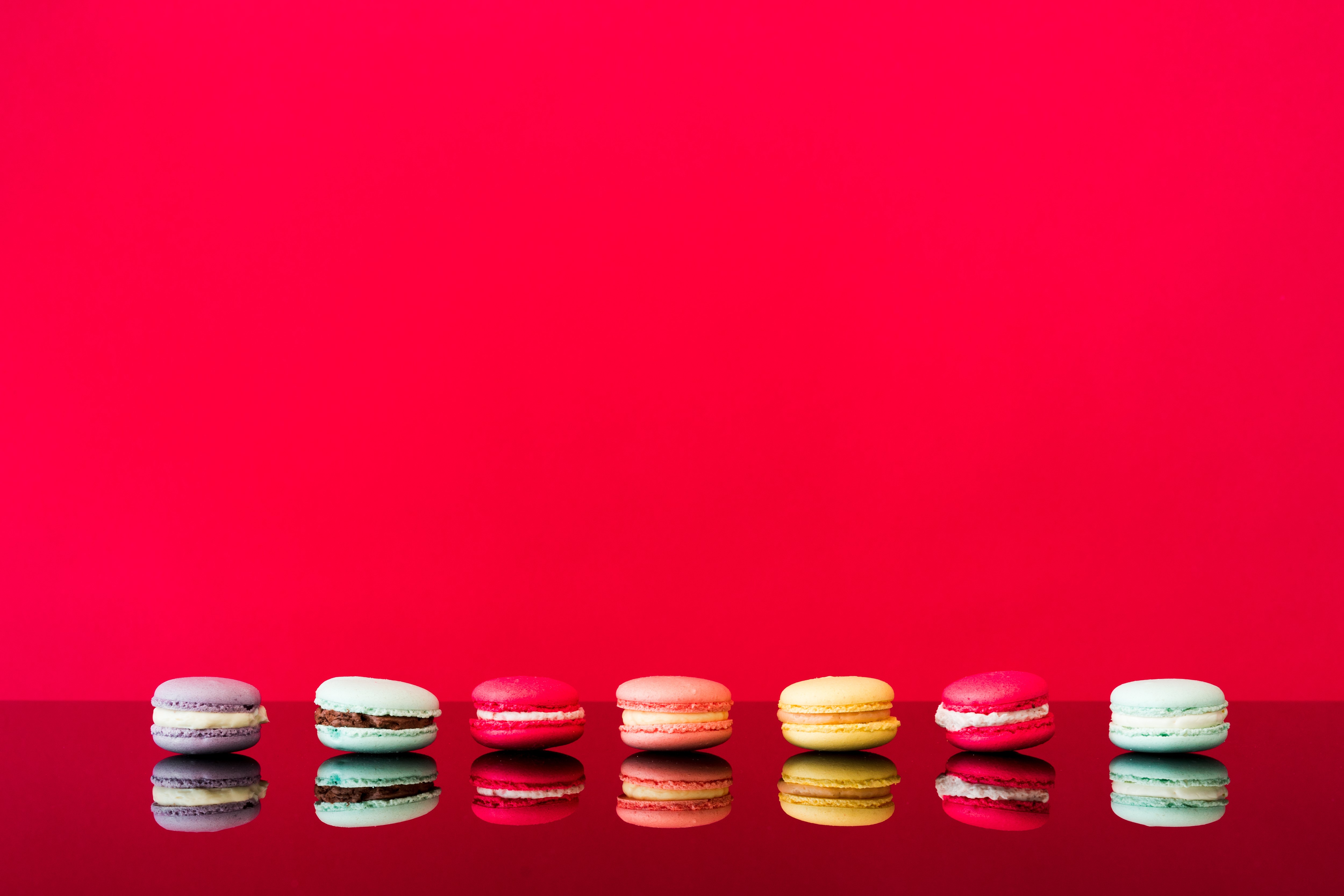 Macarons on a red background with reflection HD Wallpaper