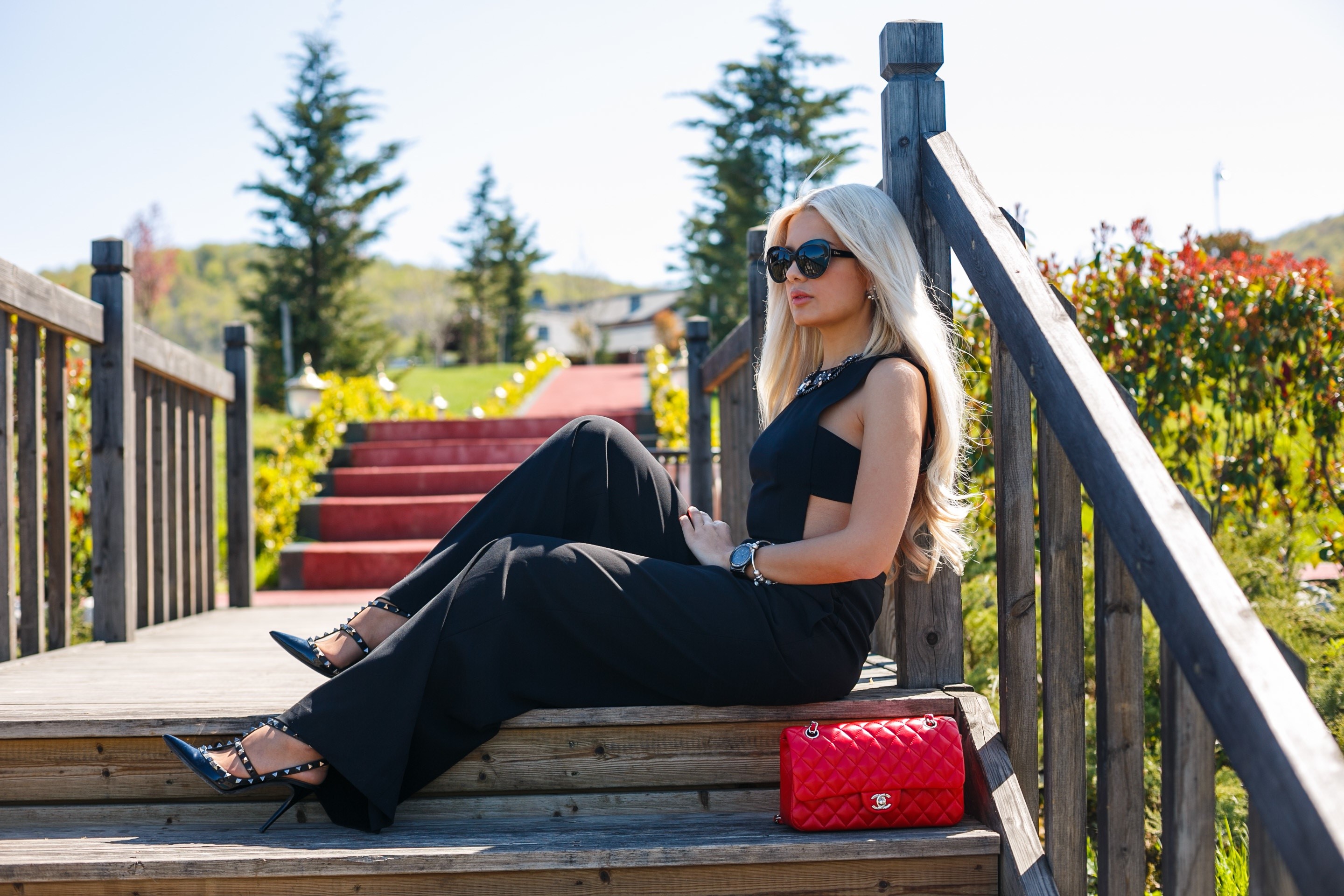 Woman in black jumpsuit sitting on wooden stairs with red handbag HD Wallpaper