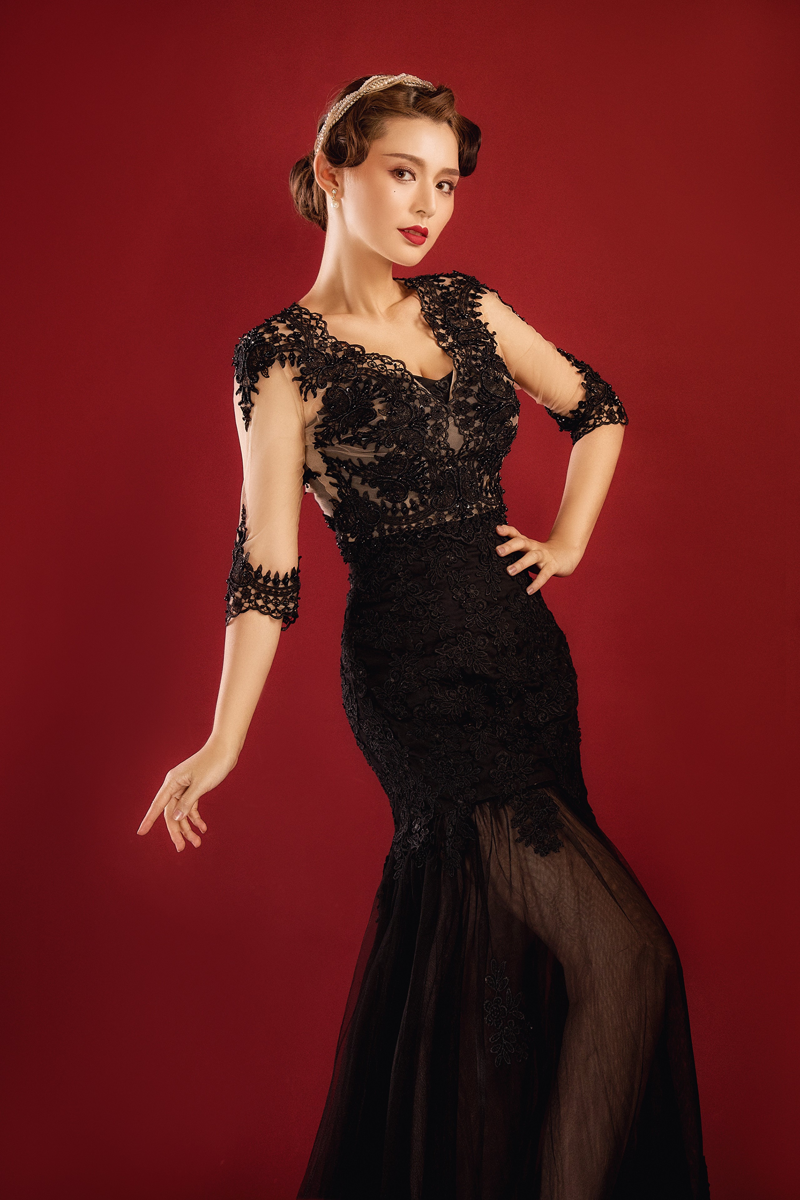 Woman in black lace dress posing against red background HD Phone Wallpaper