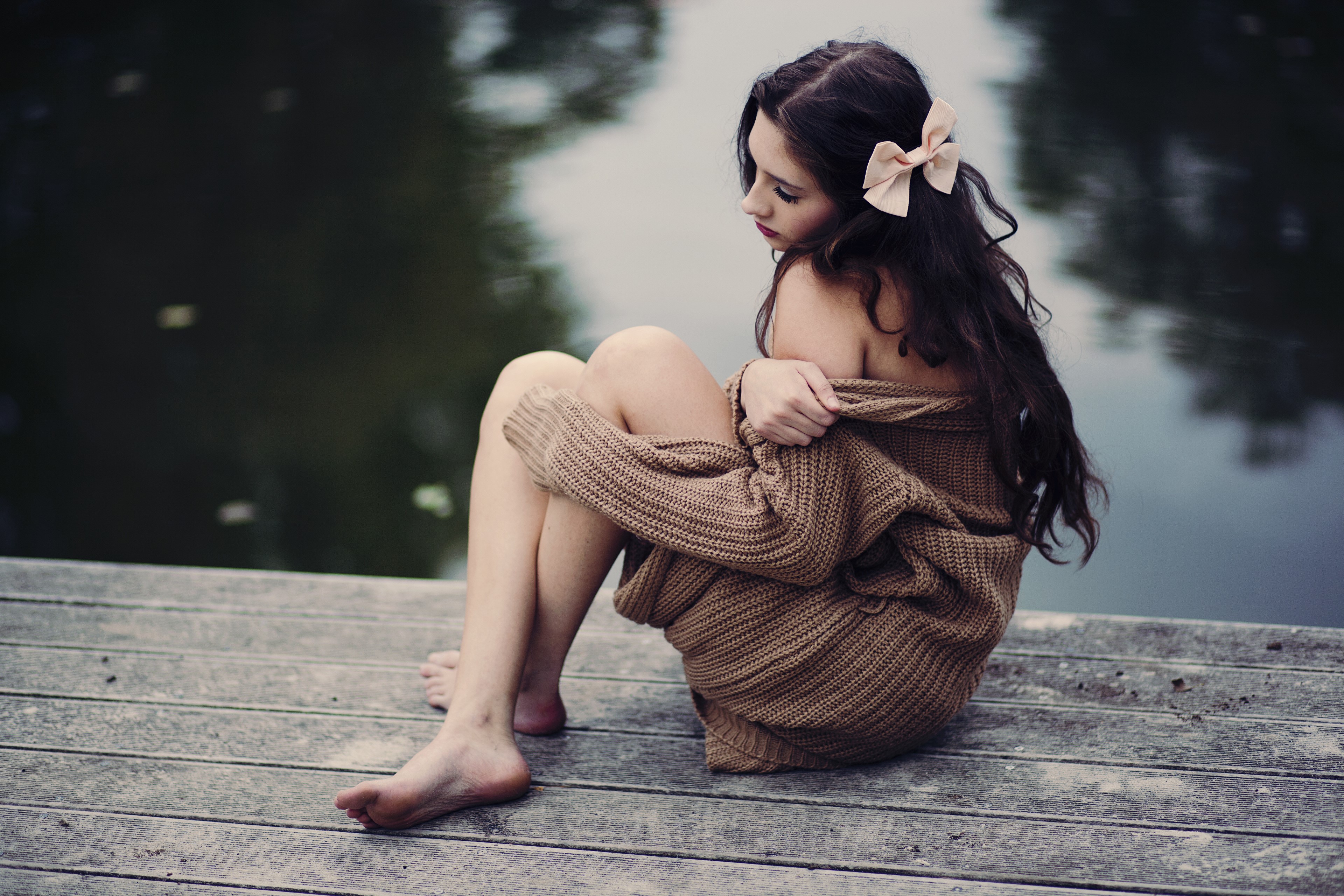 Brunette girl in sweater sitting on a dock HD Wallpaper