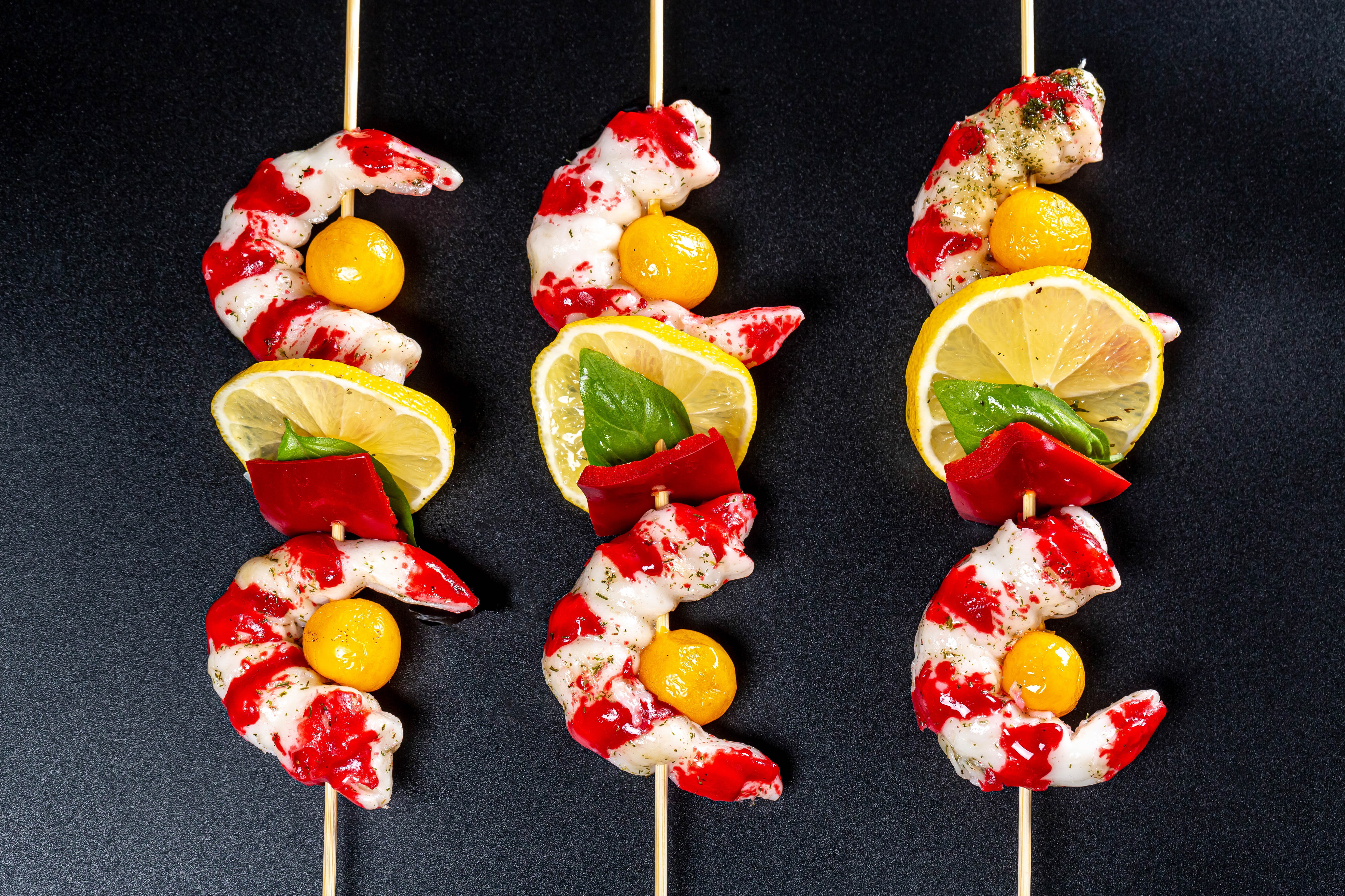 Shrimp skewers with lemon and red pepper on a dark background HD Wallpaper