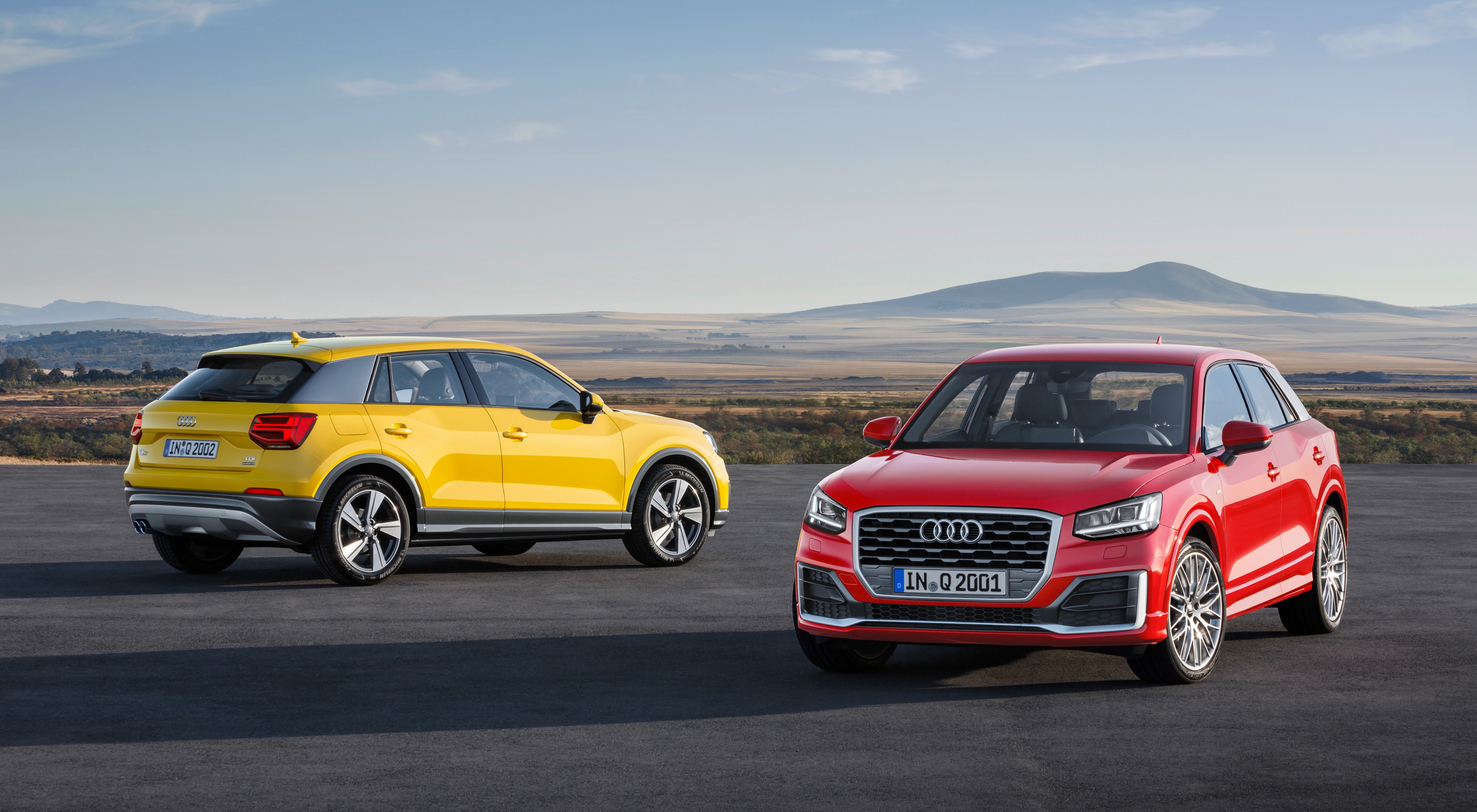 Two Audi Q2 cars, yellow and red, outdoors HD Wallpaper