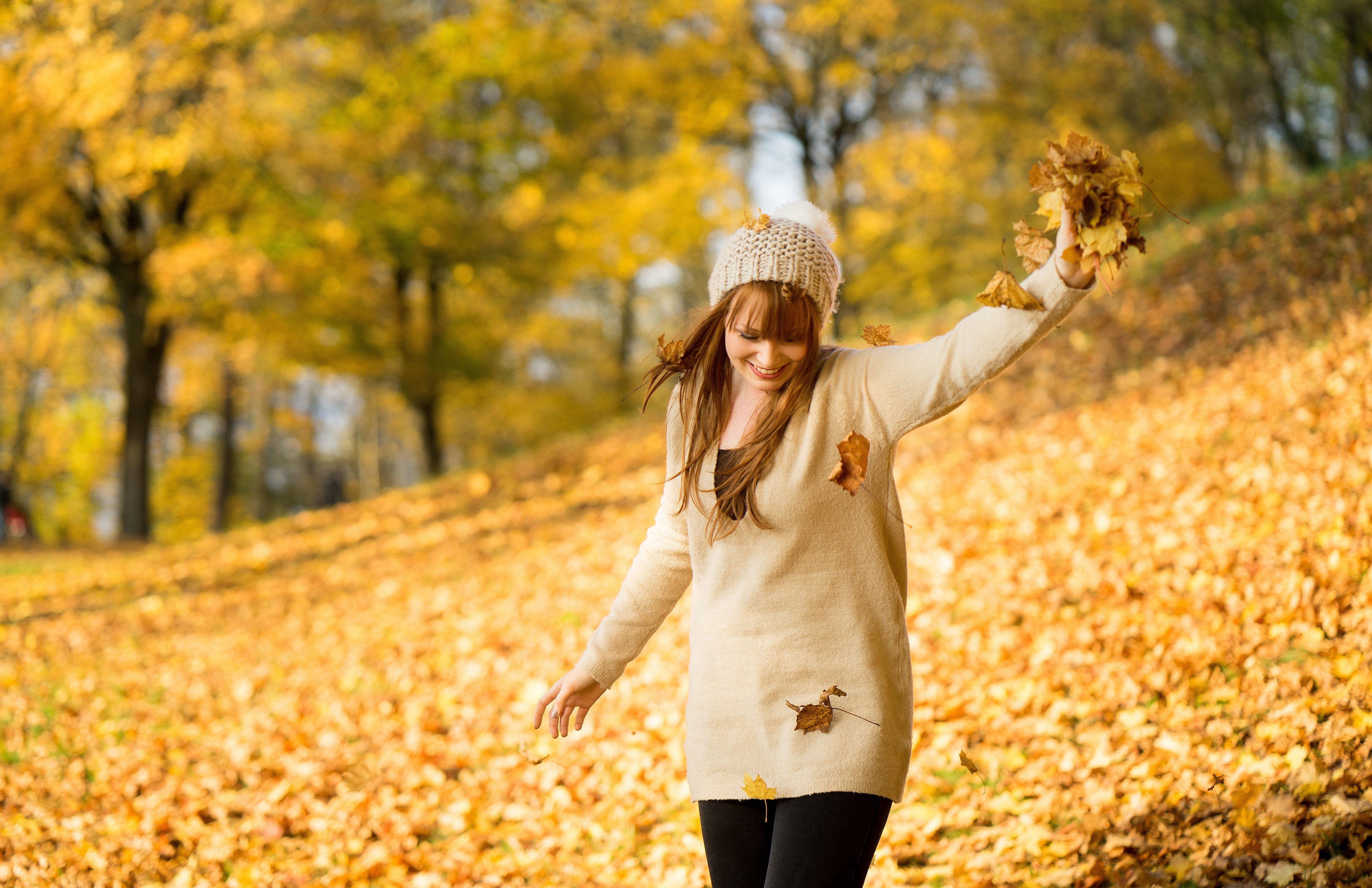 Woman in sweater and winter hat throwing leaves HD Wallpaper