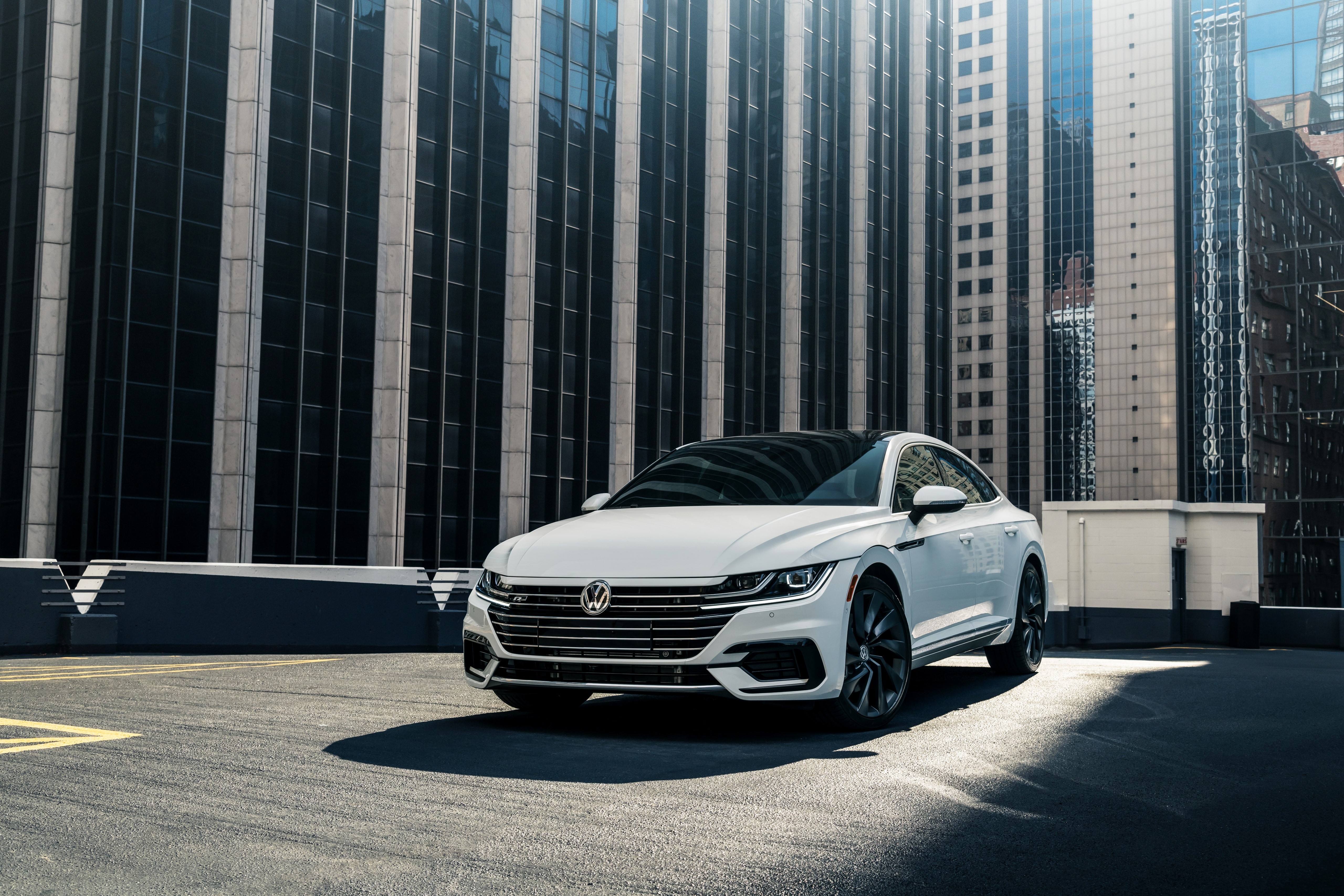 White Volkswagen Arteon R-Line parked in front of modern buildings HD Wallpaper