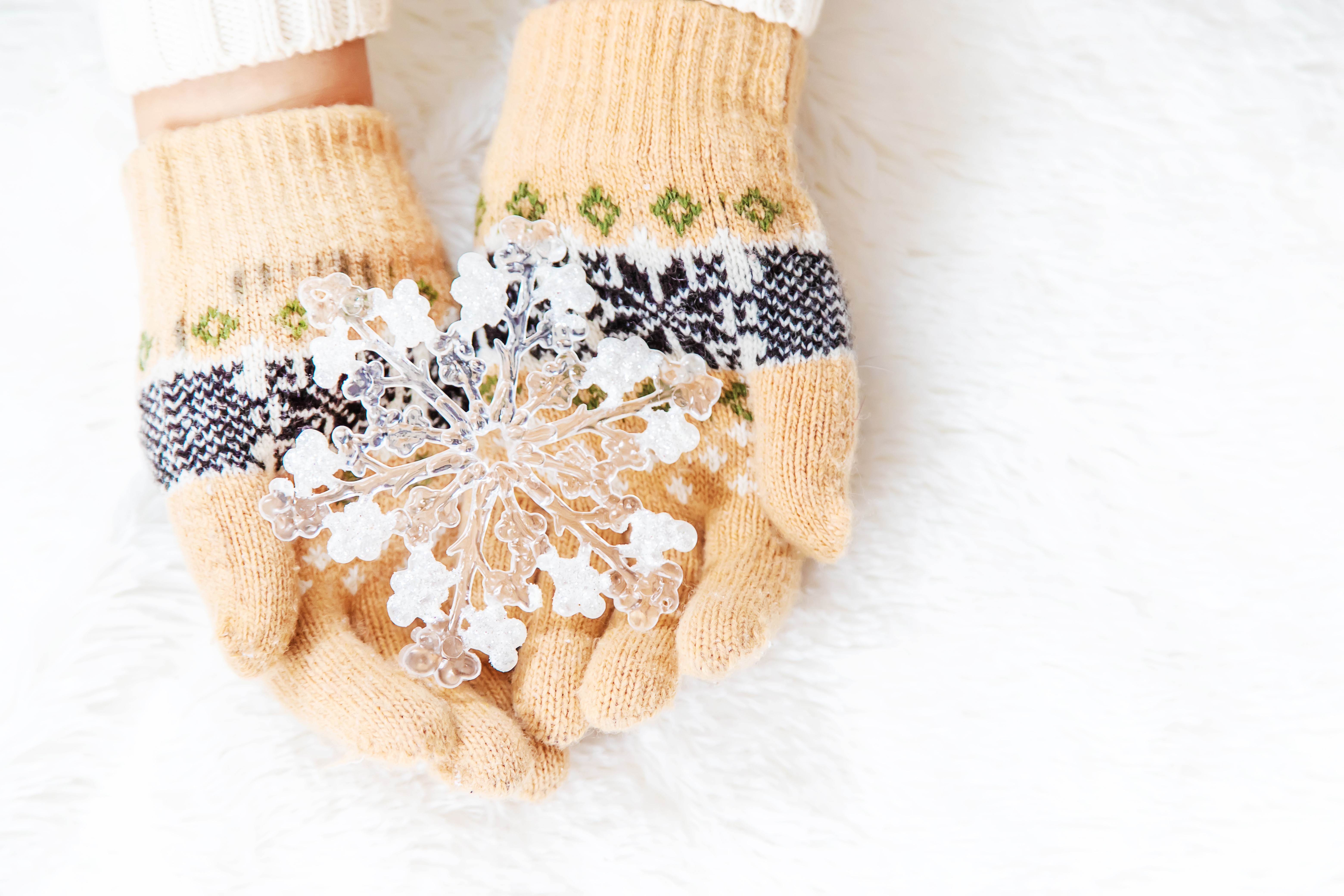 Hands in patterned gloves holding a snowflake HD Wallpaper