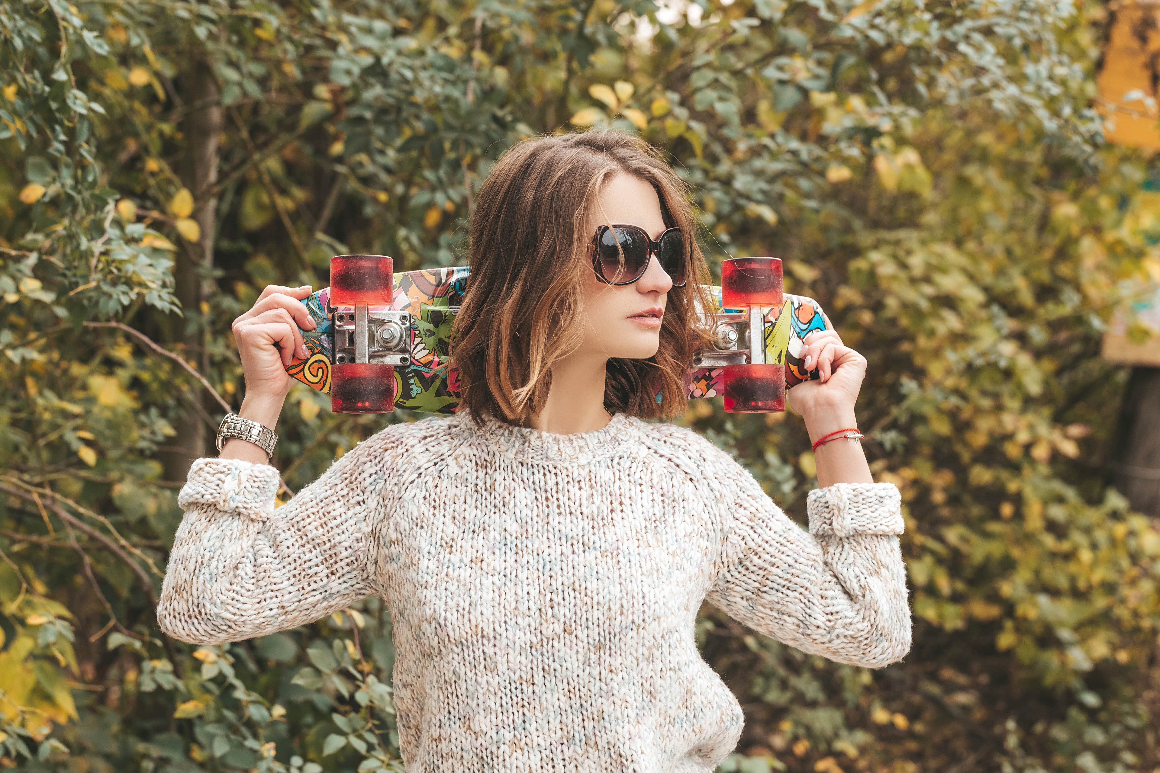 Woman with Skateboard Wearing Sweater and Glasses HD Wallpaper