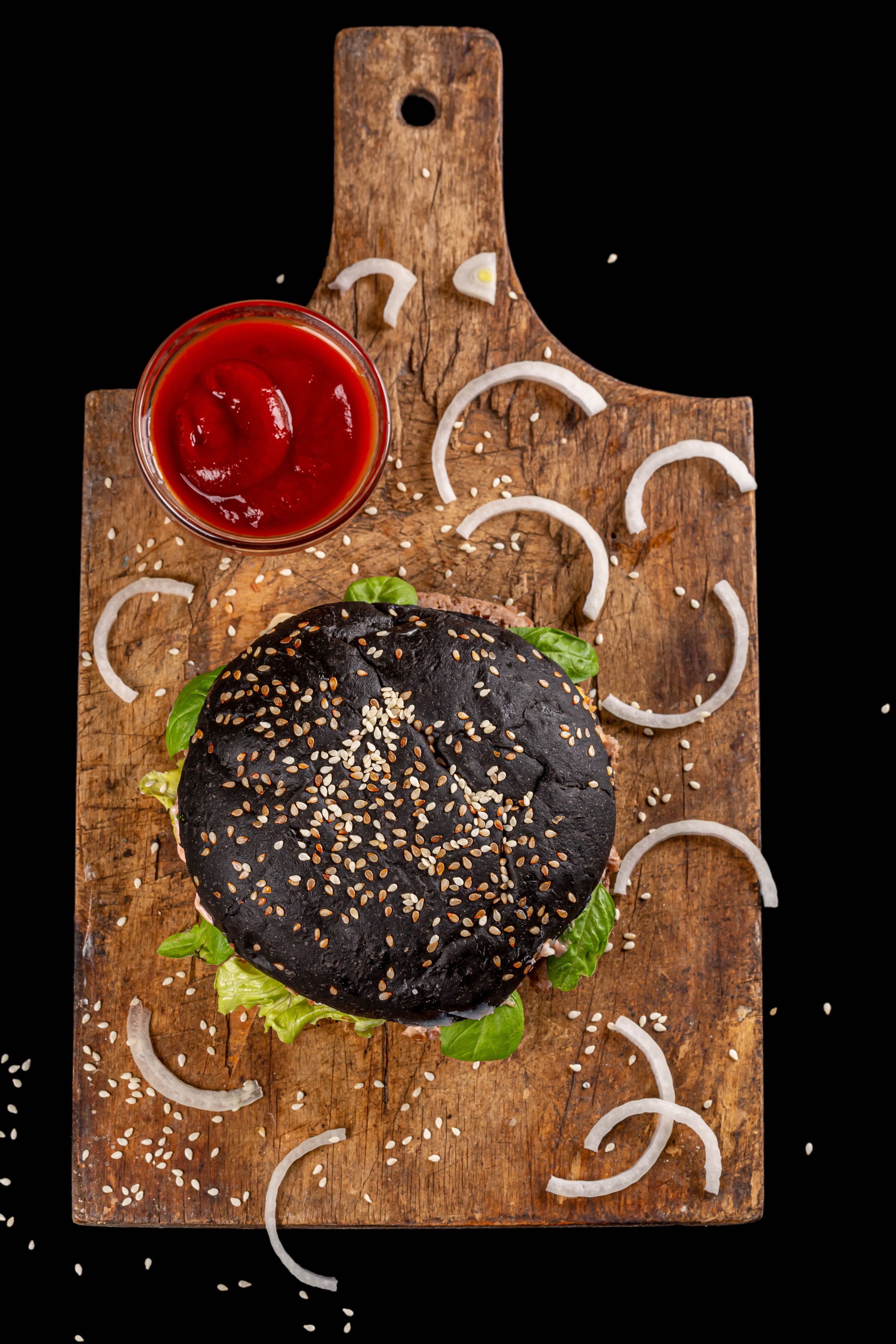 Black hamburger with ketchup on a wooden cutting board HD Phone Wallpaper