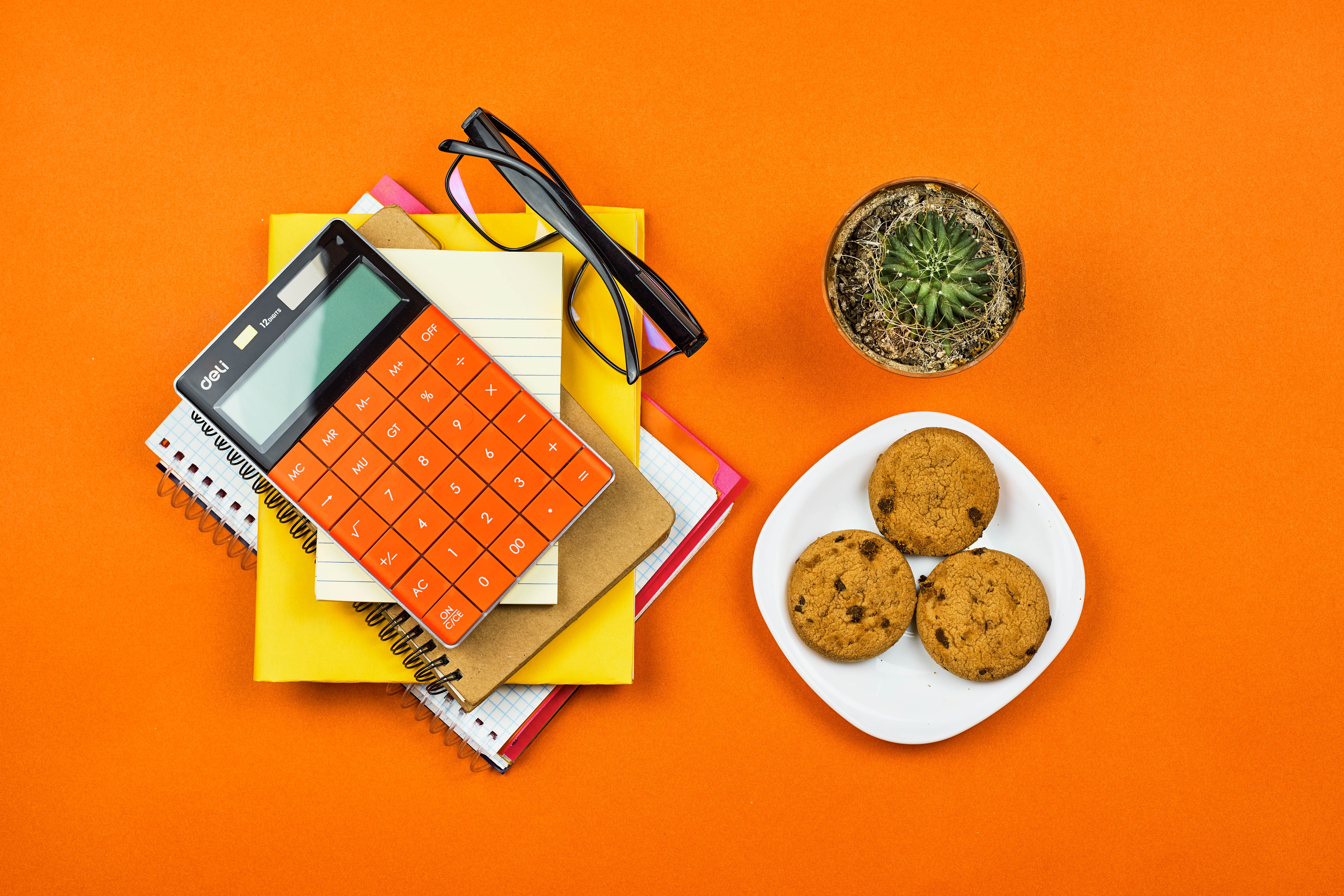 Calculator, notepad, glasses, cactus, and cookies on orange background HD Wallpaper