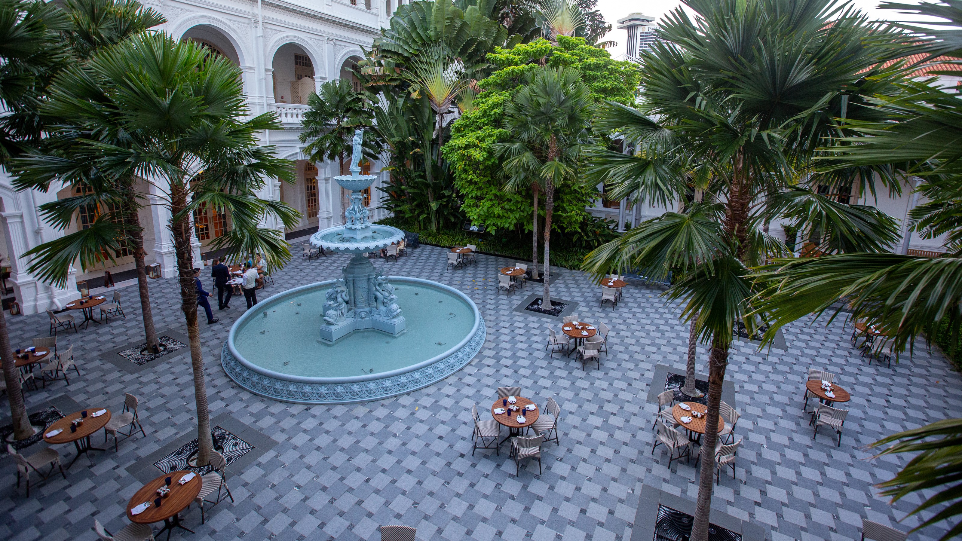 Raffles Hotel courtyard with fountain and palm trees HD Wallpaper