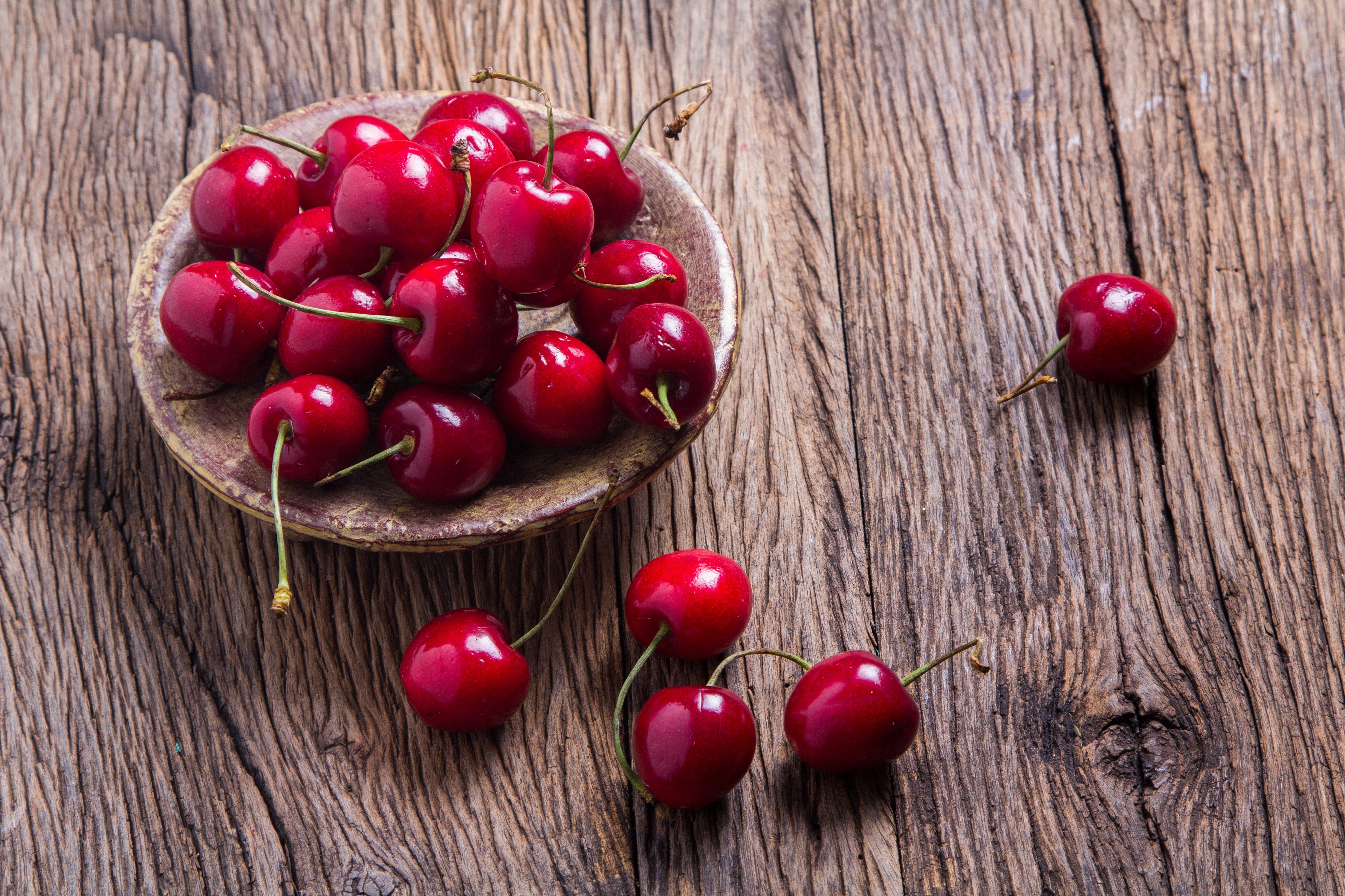 Cherries in a saucer on a wooden table HD Wallpaper