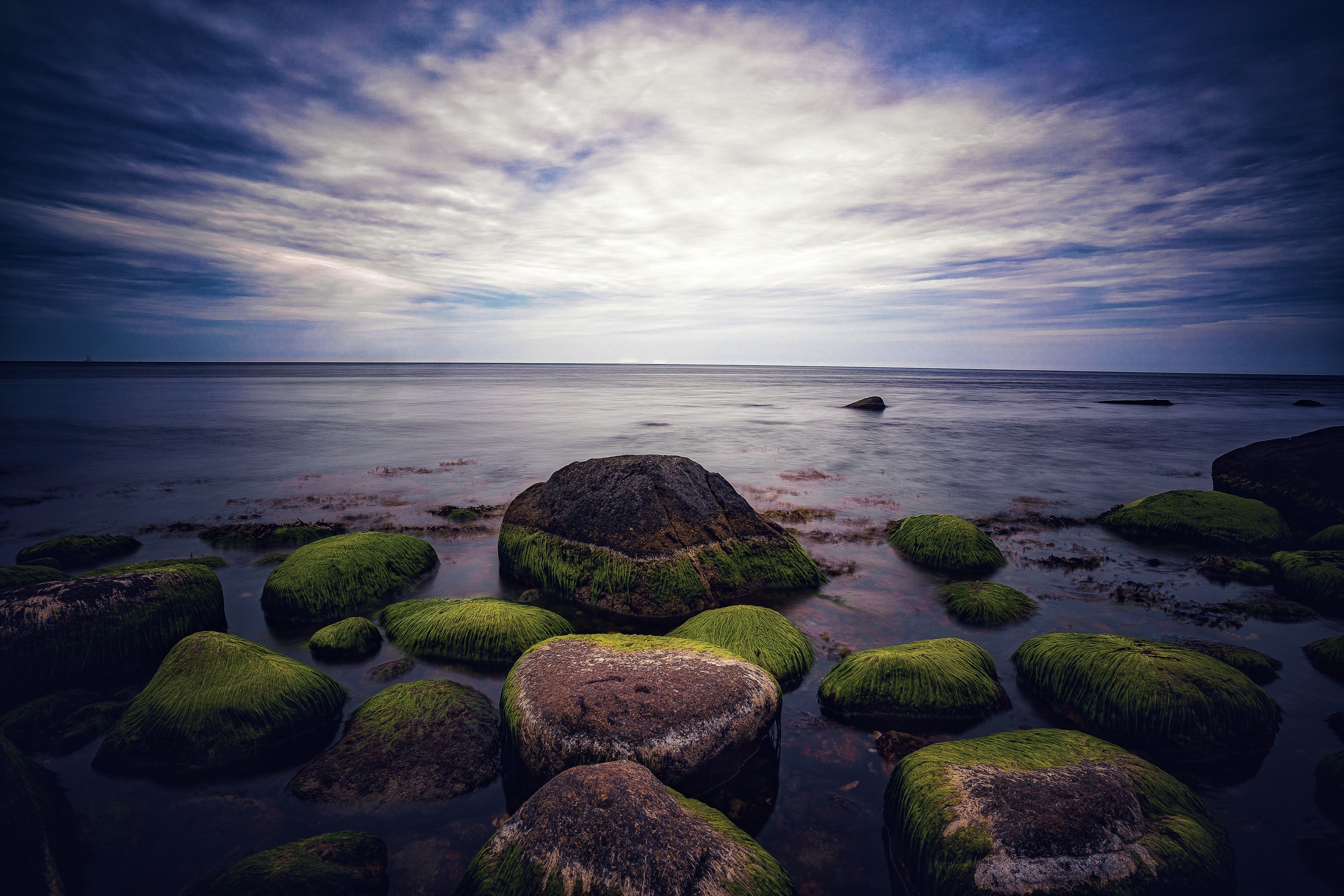 Ocean with mossy stones at dusk HD Wallpaper