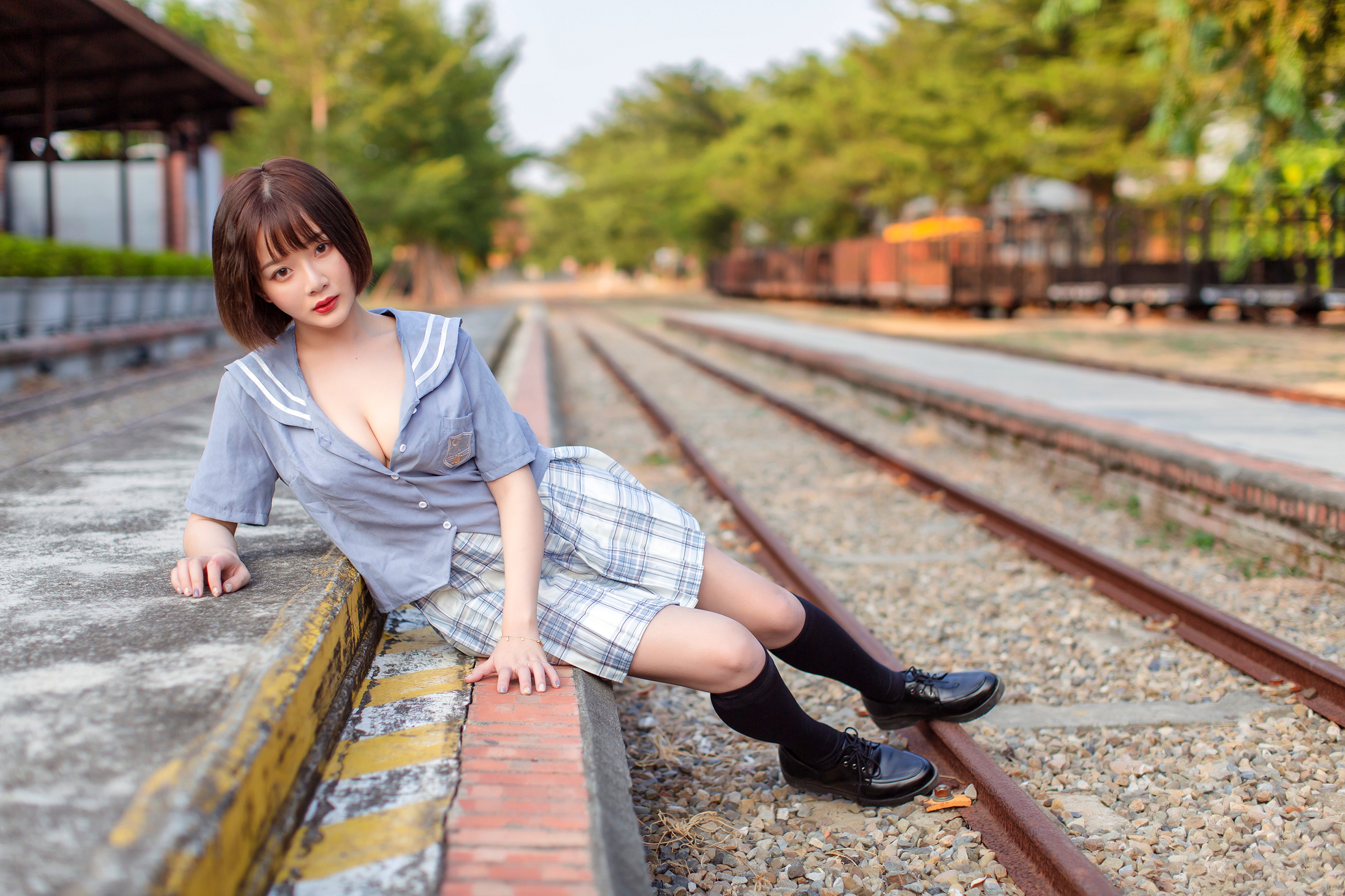 Asian woman with brown hair sitting on train tracks HD Wallpaper