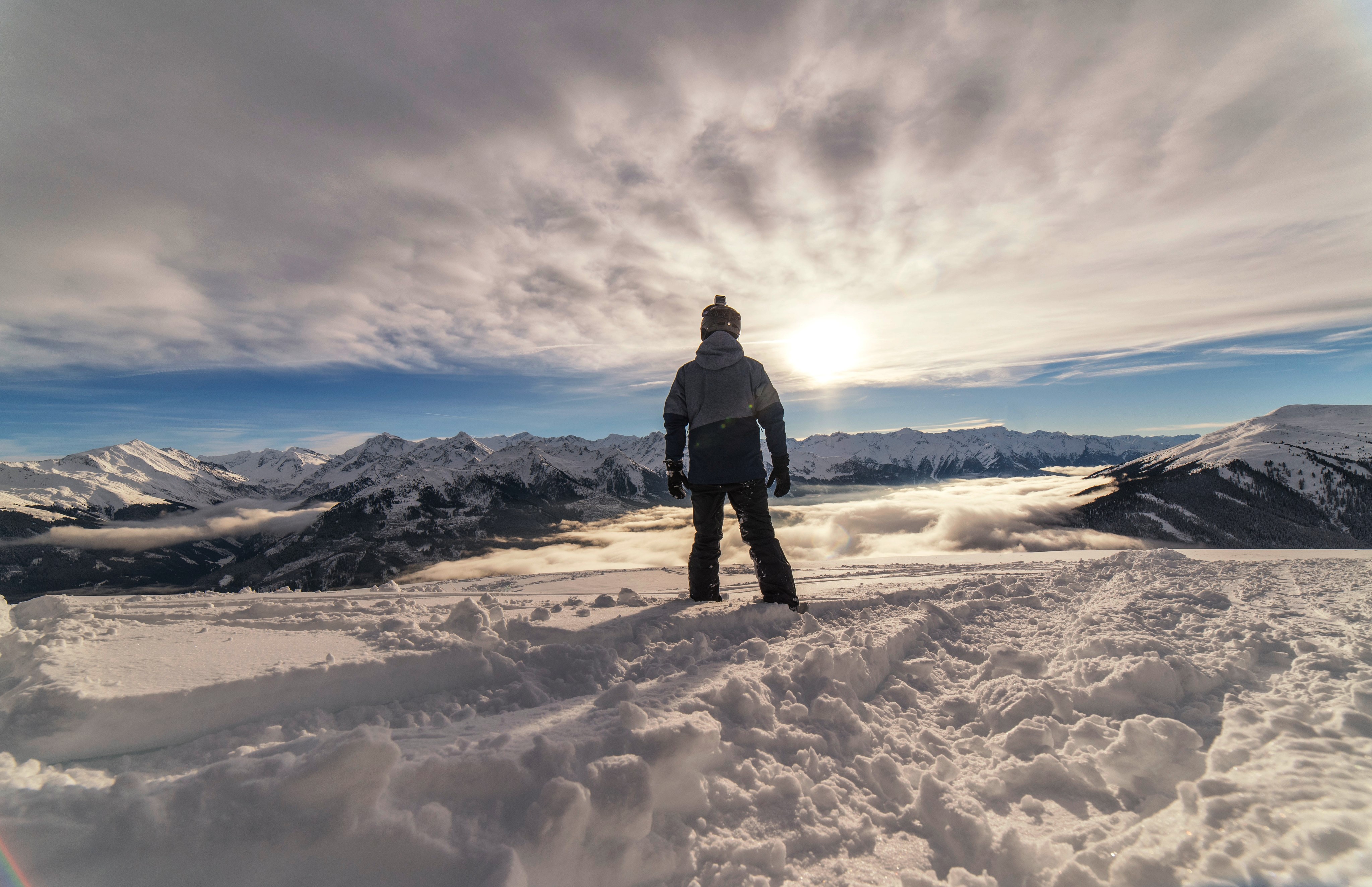 Snowboarder on a mountain peak overlooking clouds HD Wallpaper