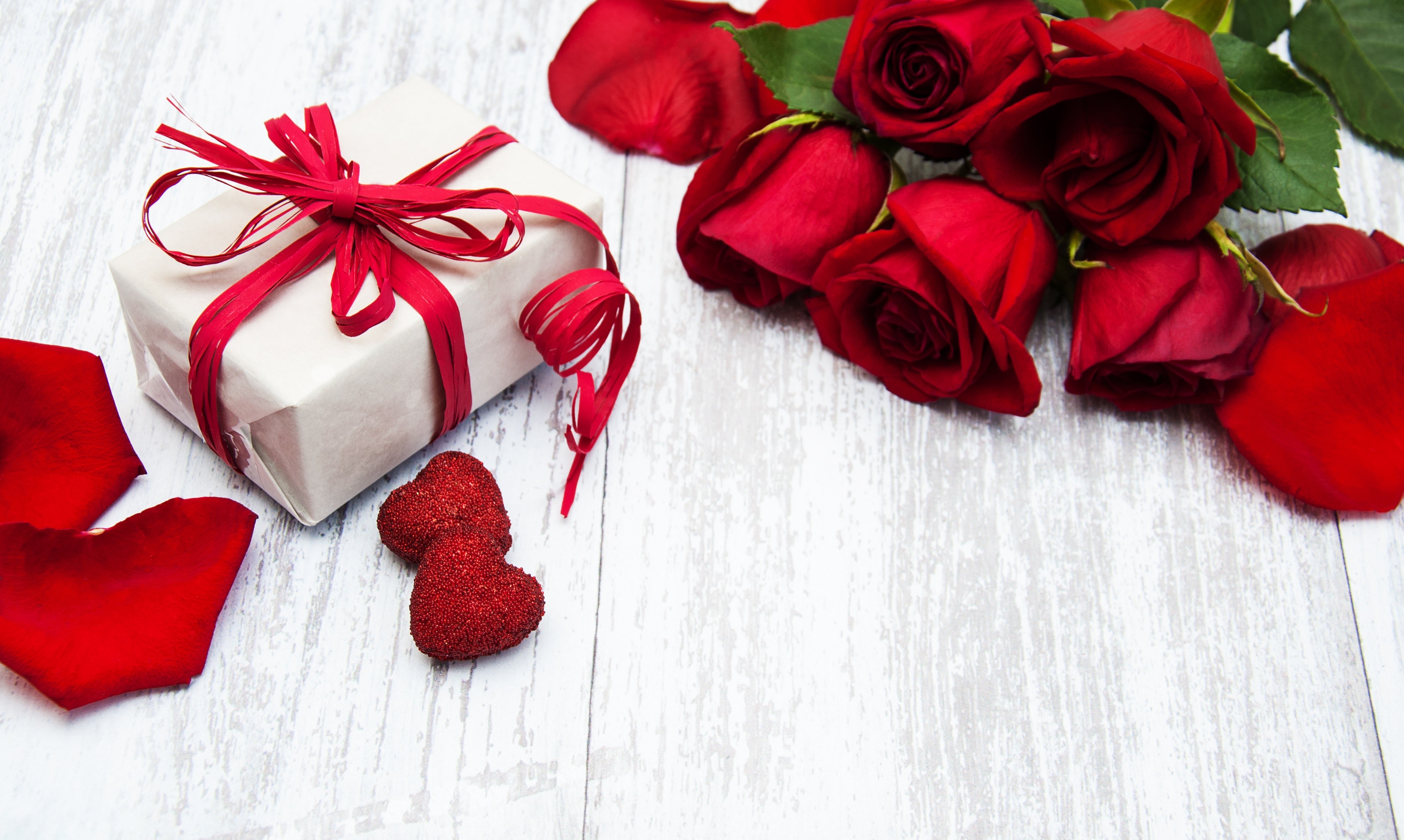 Gift box with red roses and petals on a wooden table HD Wallpaper