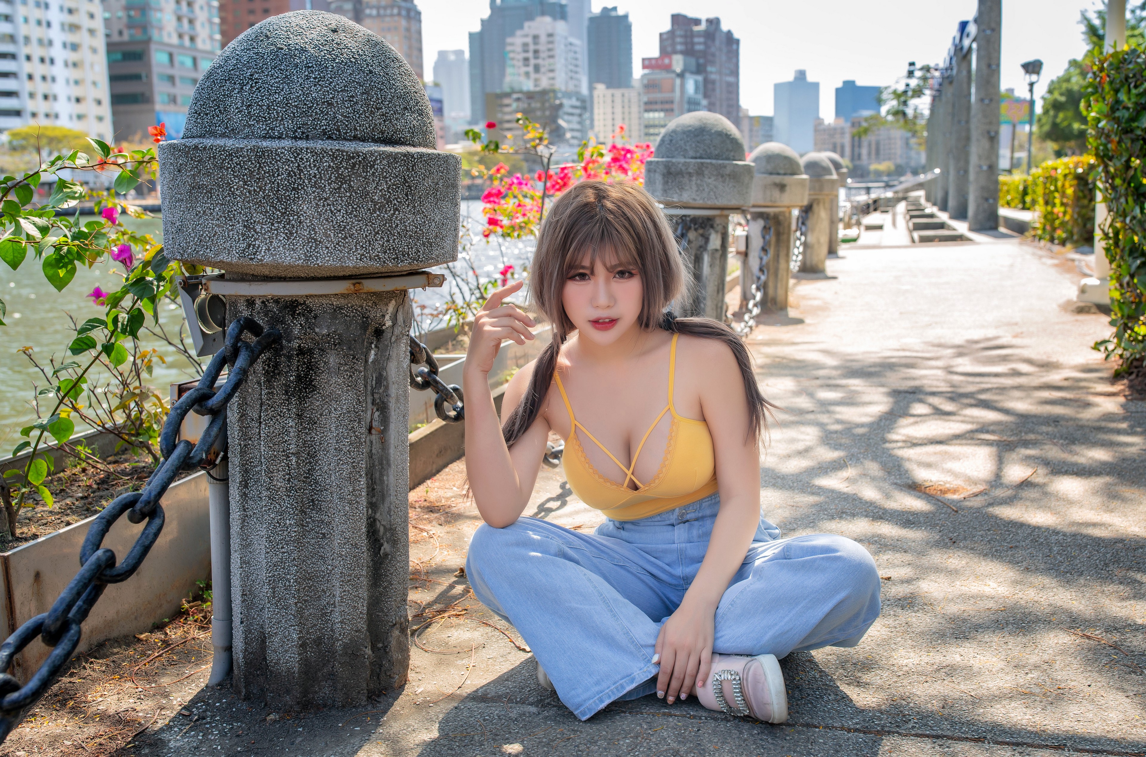 Asian woman in yellow singlet and jeans sitting outdoors HD Wallpaper