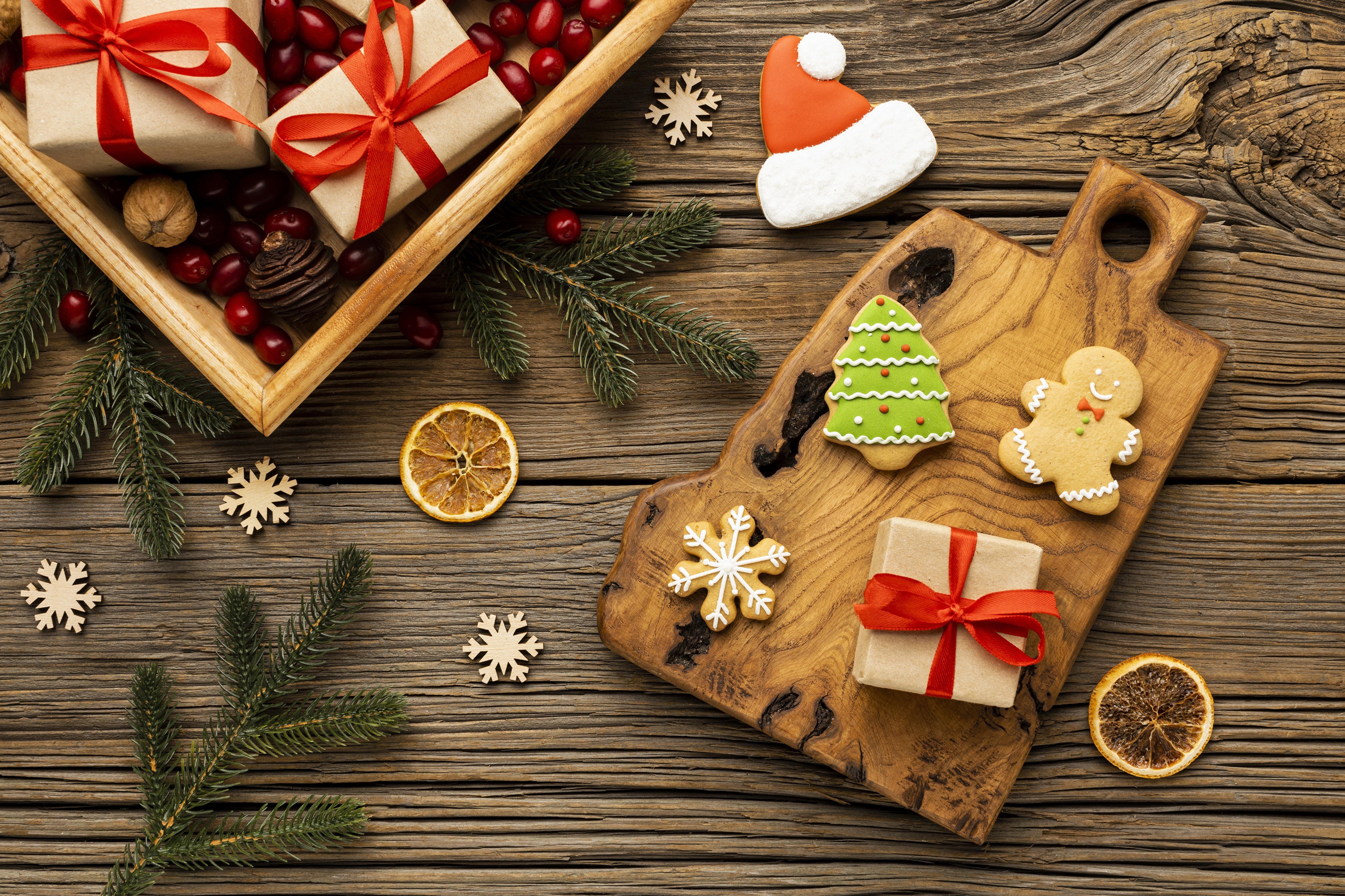 Christmas gifts, cookies, and pine branches on a wooden table HD Wallpaper