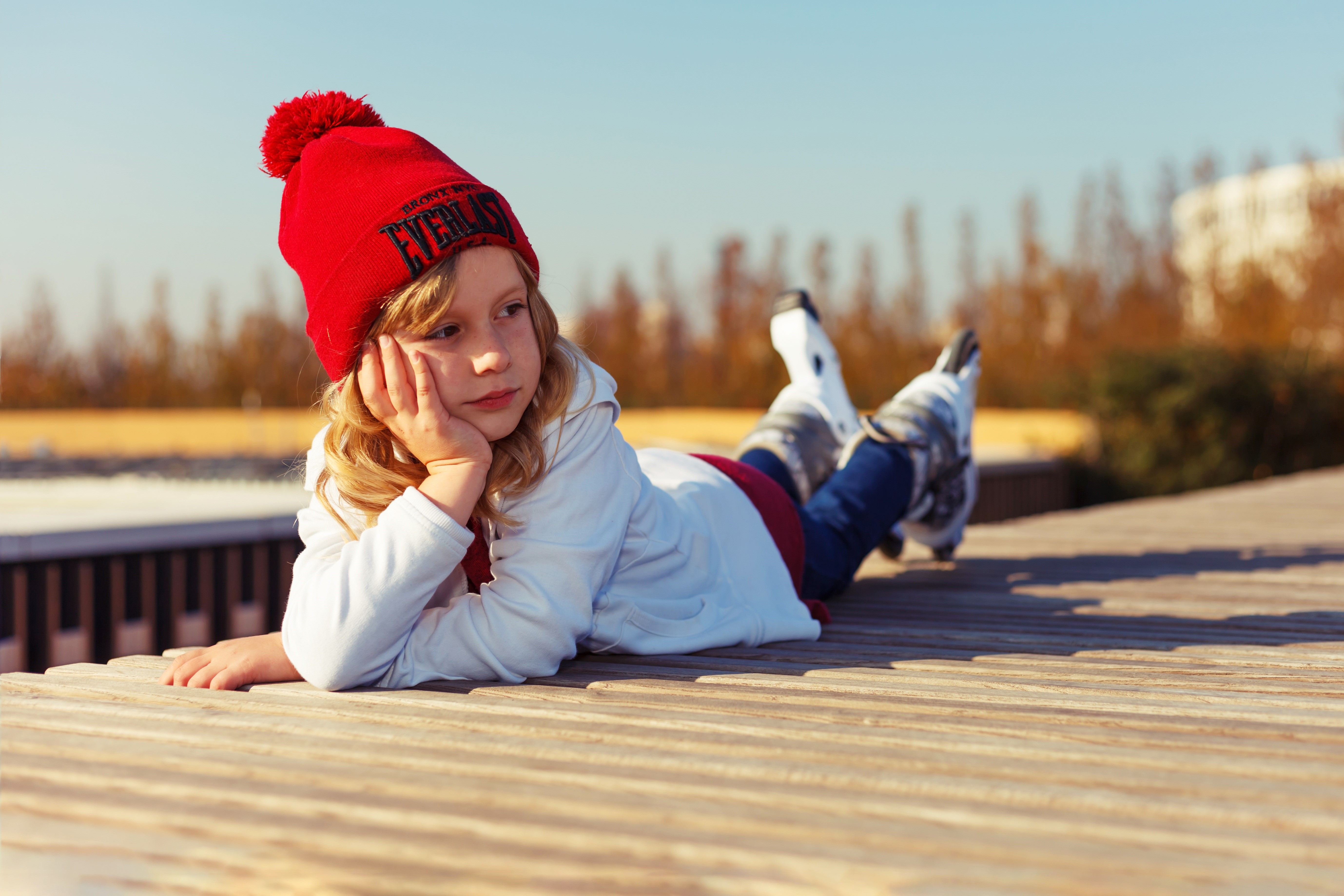 Girl in winter hat and roller skates lying down HD Wallpaper