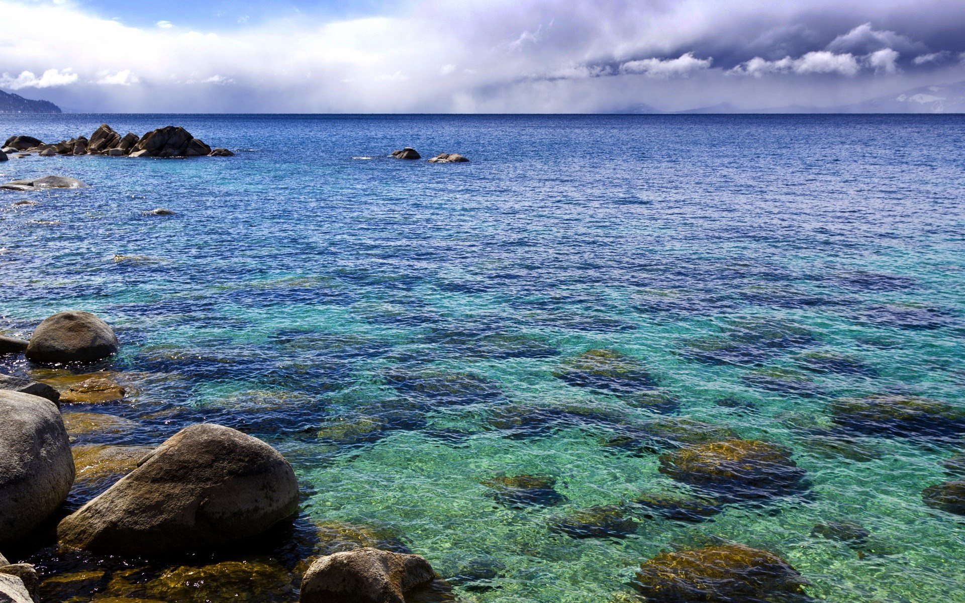 Clear blue water with rocks and cloudy sky HD Wallpaper