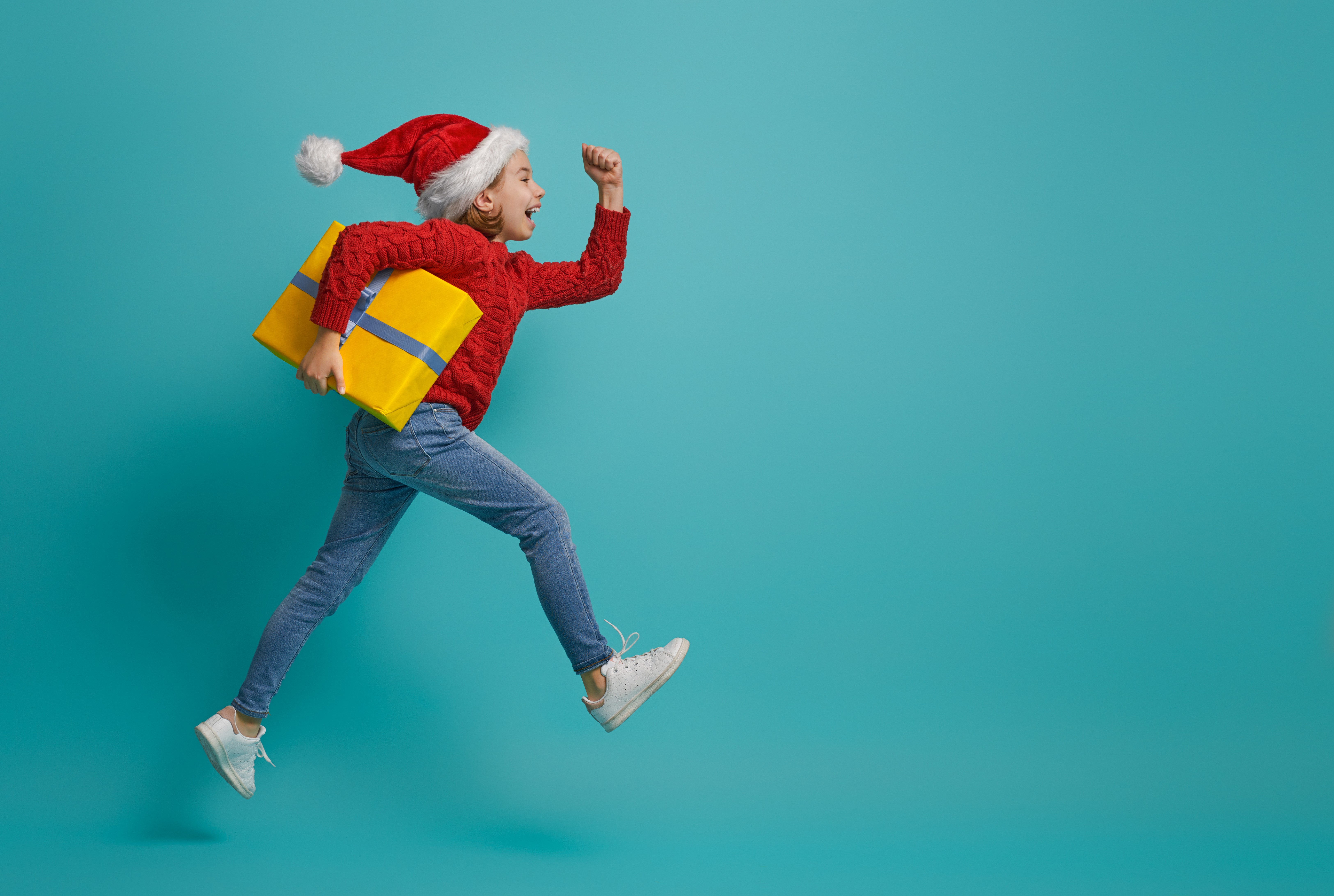 Girl in Santa hat running with Christmas gift HD Wallpaper