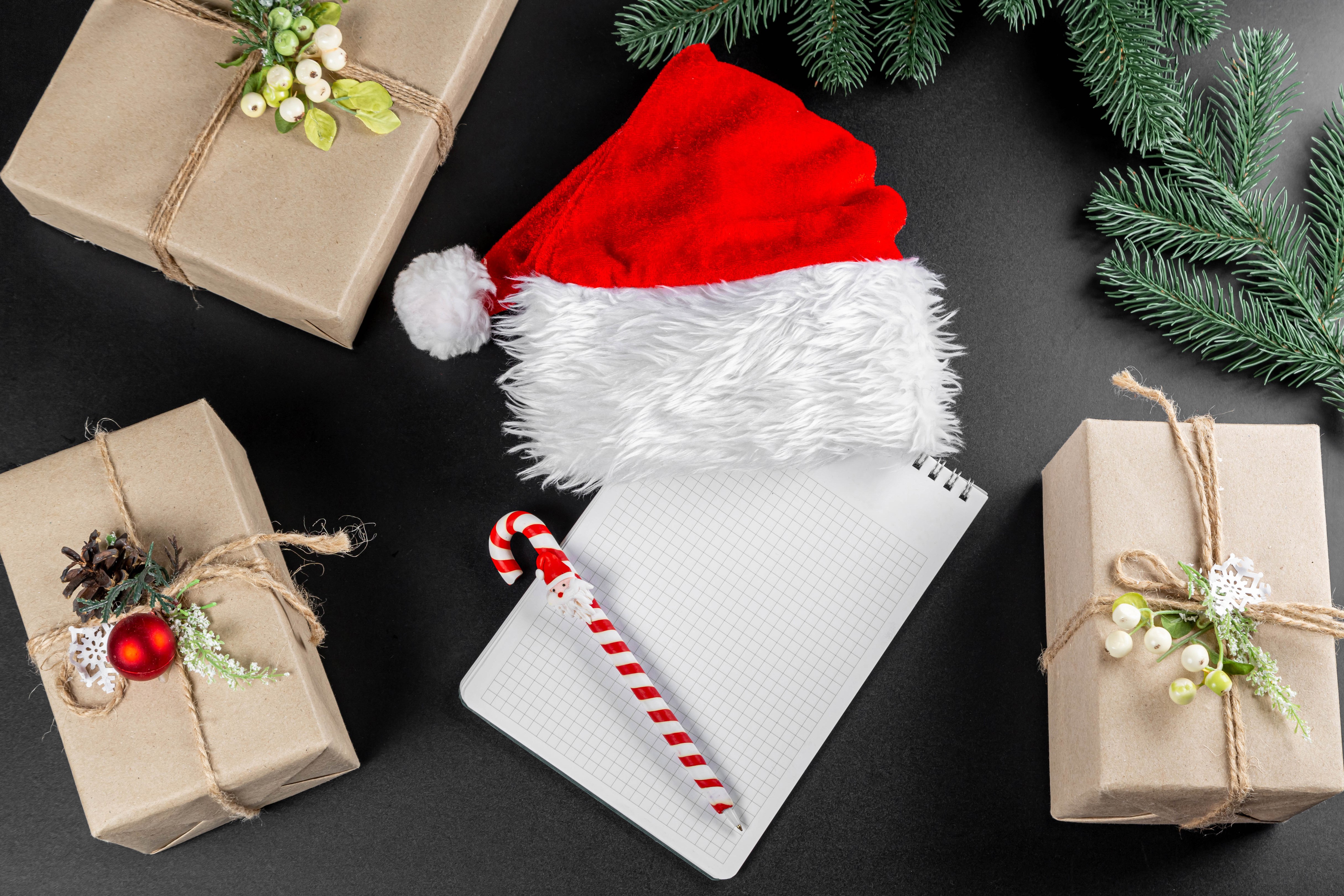 Christmas gifts, Santa hat, notepad, and pen on black background HD Wallpaper