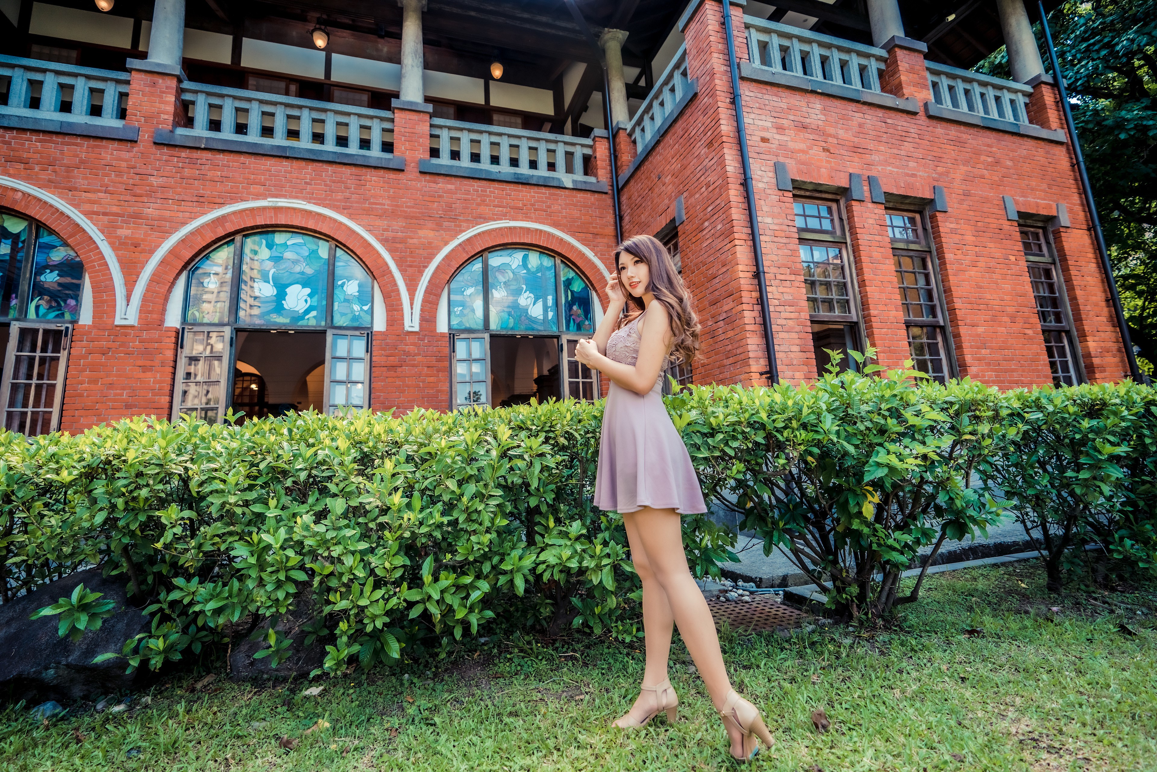 Asian woman in dress posing near red brick building HD Wallpaper