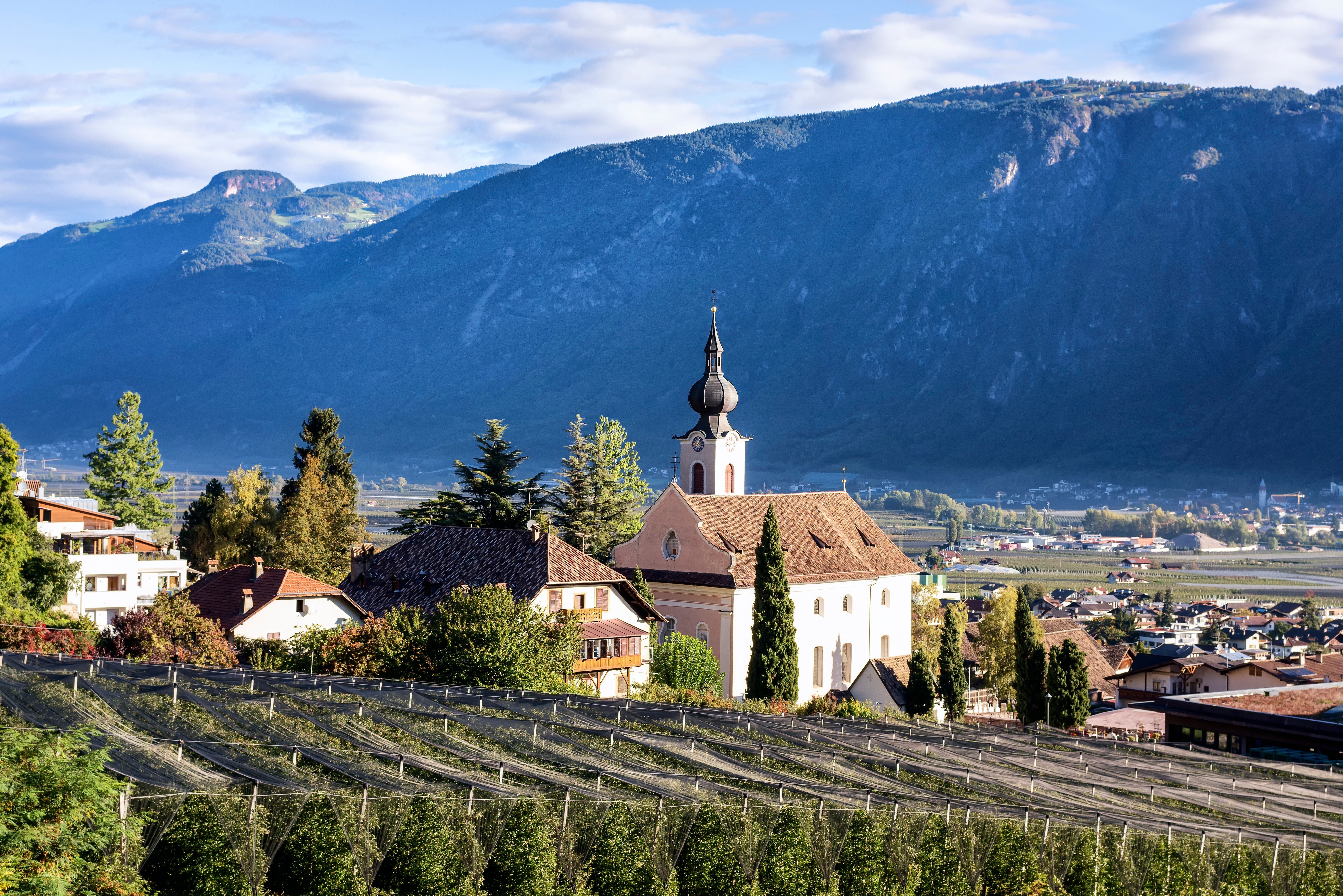 Church and houses in Nalles, Italy with Alps mountains HD Wallpaper