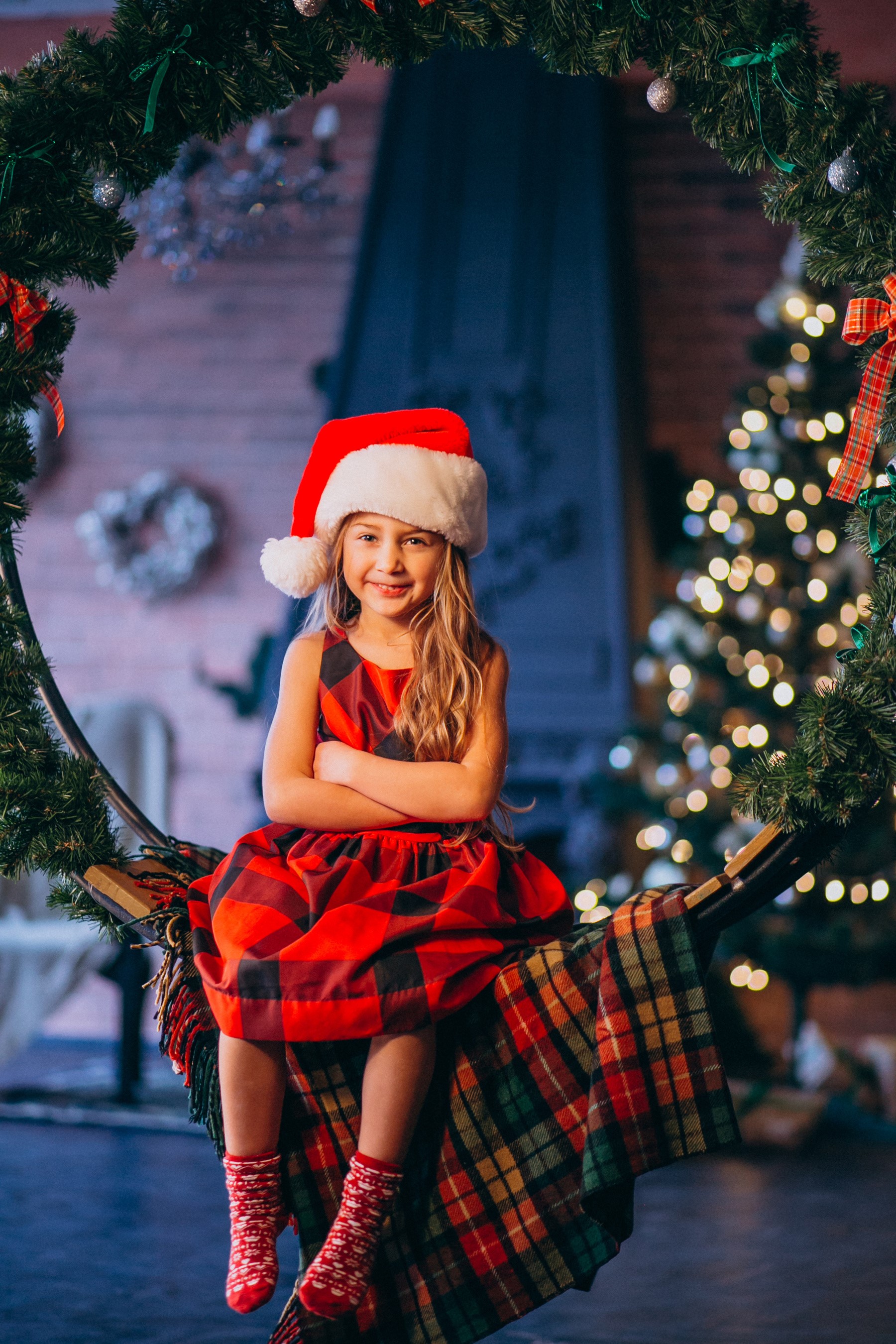 Girl in Santa hat sitting on a swing with Christmas decorations HD Phone Wallpaper