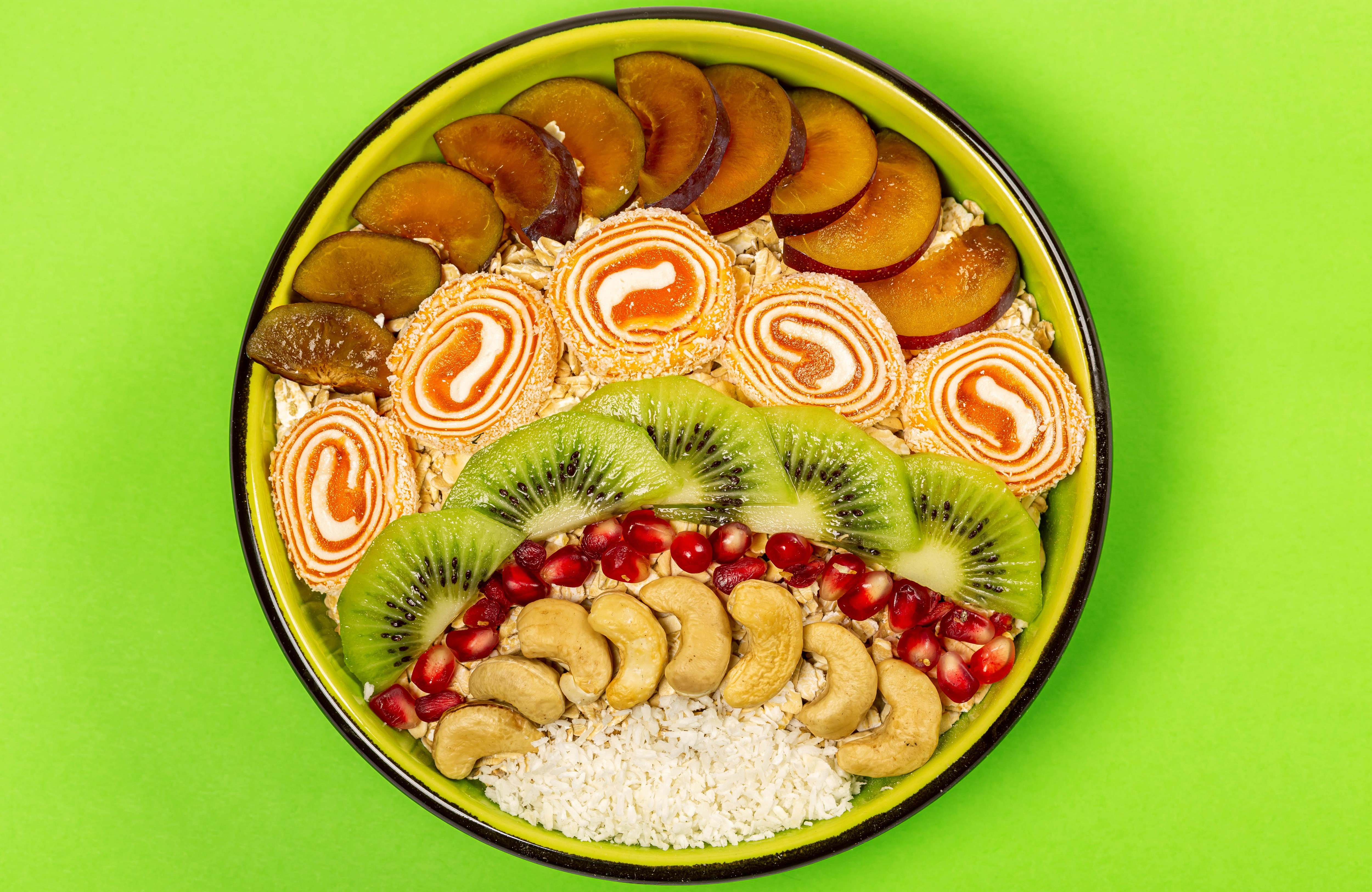Oatmeal bowl with kiwi, plums, marmalade, pomegranate, and nuts HD Wallpaper