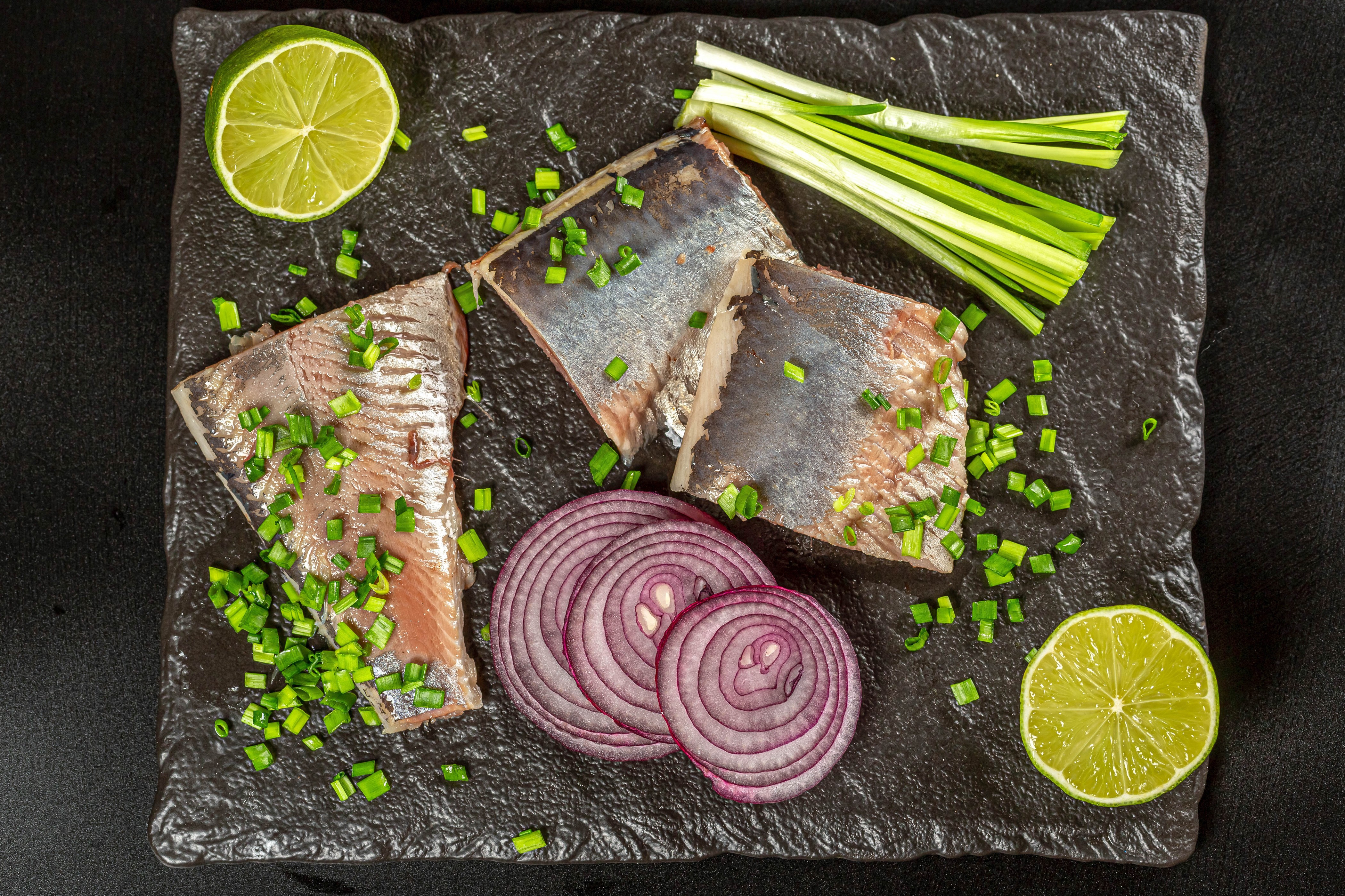 Herring fillets with red onion, lime, and scallions on a cutting board HD Wallpaper