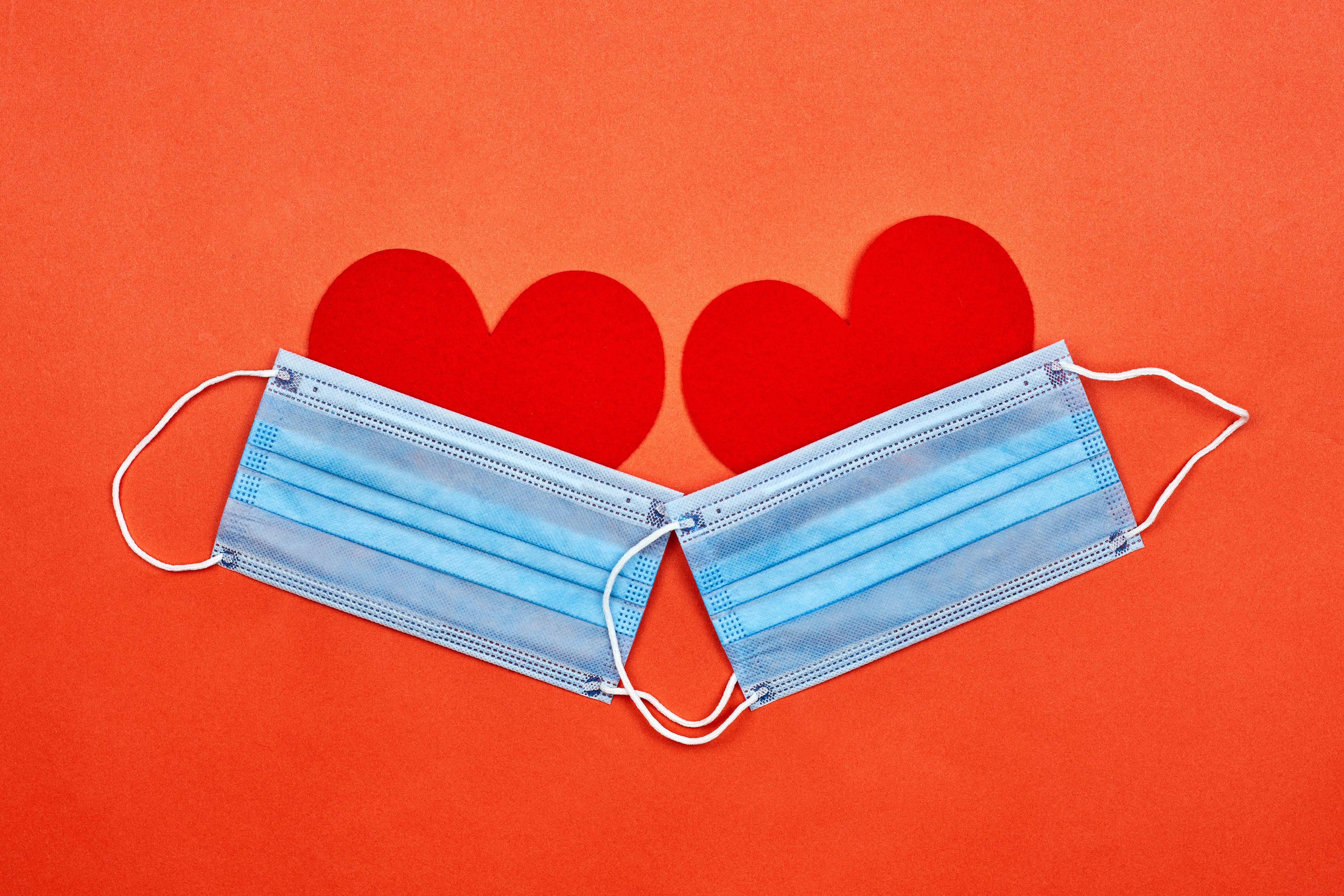 Two surgical masks and red hearts on orange background HD Wallpaper