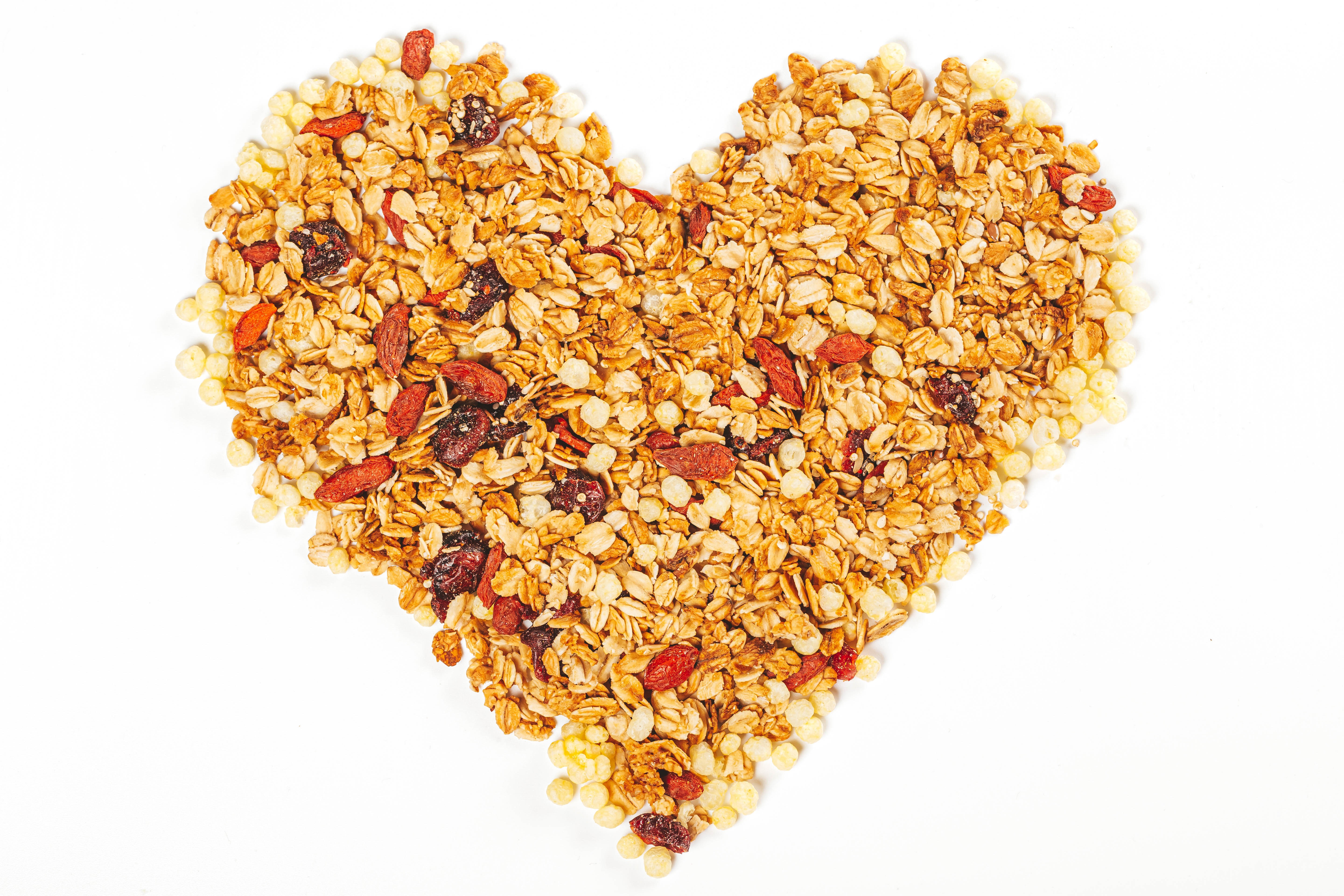 Heart shape granola with dried fruits on white background HD Wallpaper