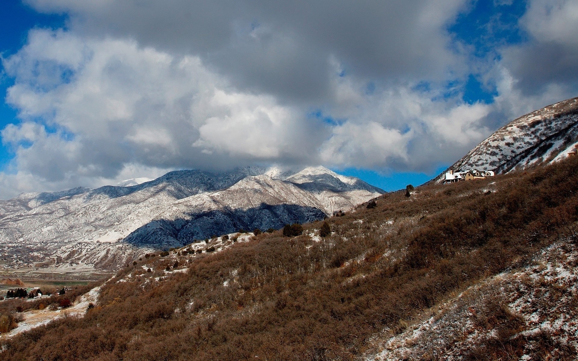 Snow-dusted mountains under a cloudy sky HD Wallpaper