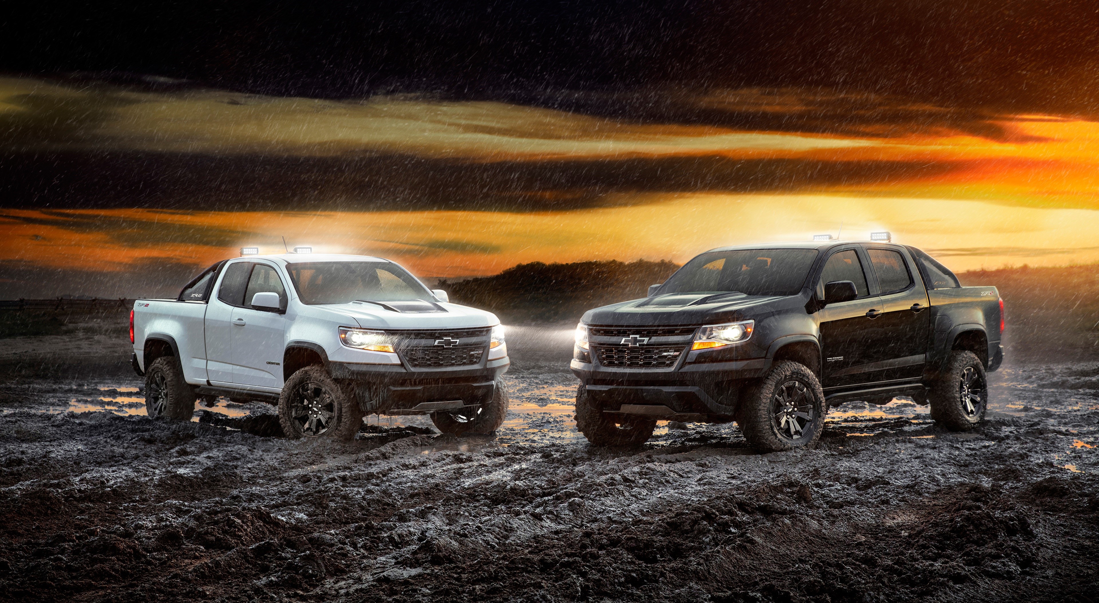 Two Chevrolet Colorado ZR2 Midnight Edition pickup trucks in mud HD Wallpaper