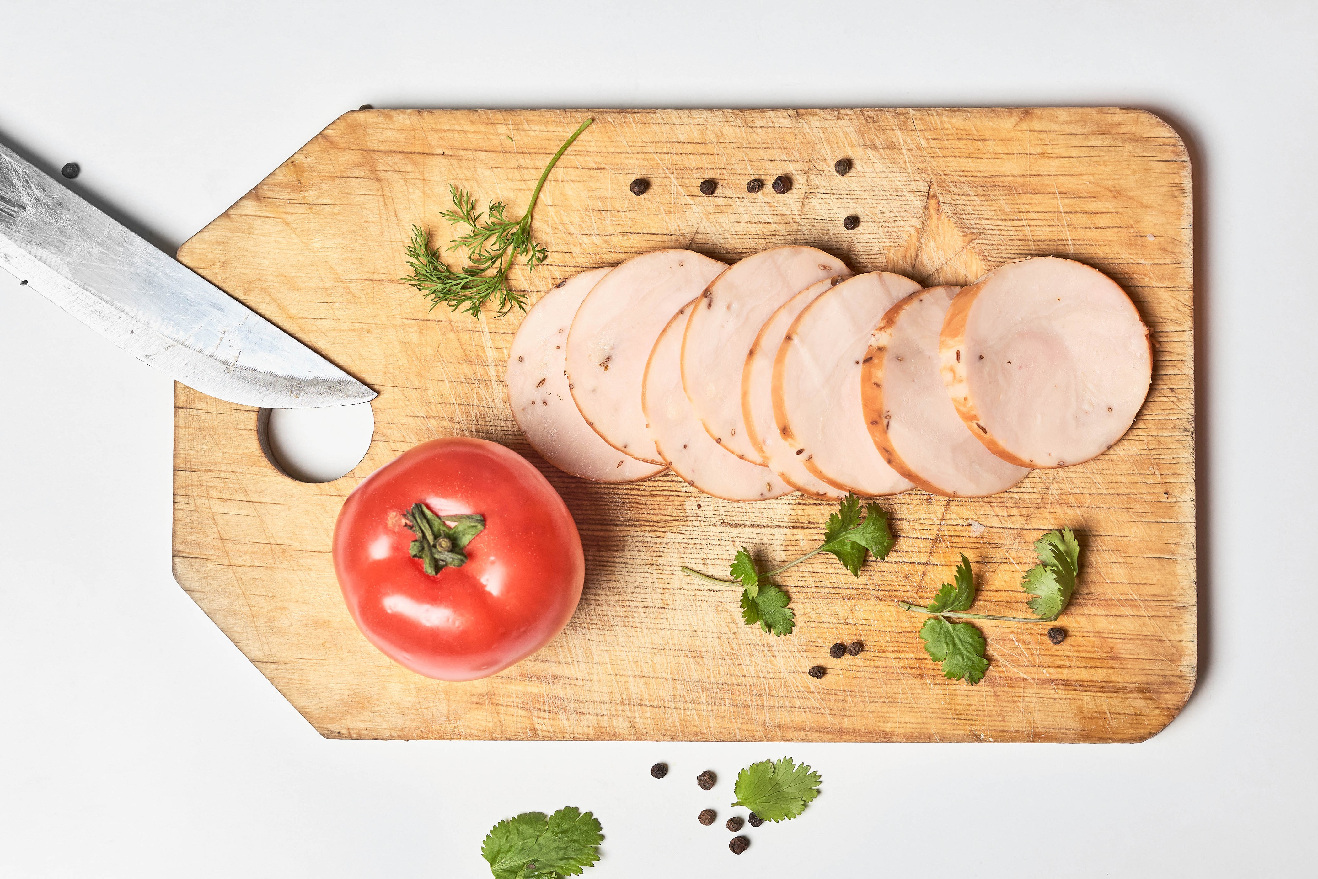 Sliced ham, tomato, and herbs on a cutting board HD Wallpaper
