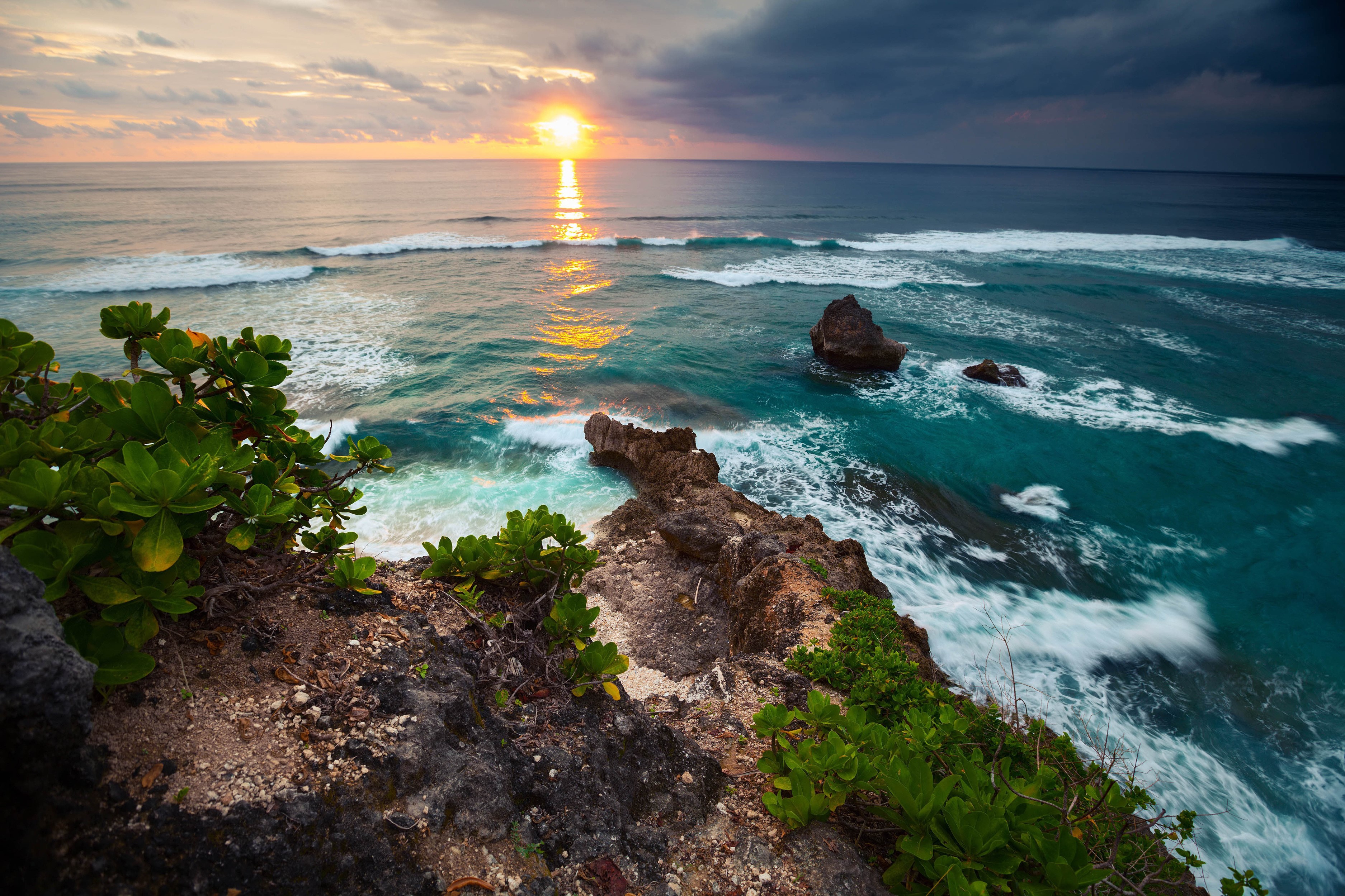 Sunset over the ocean with waves crashing on rocks HD Wallpaper