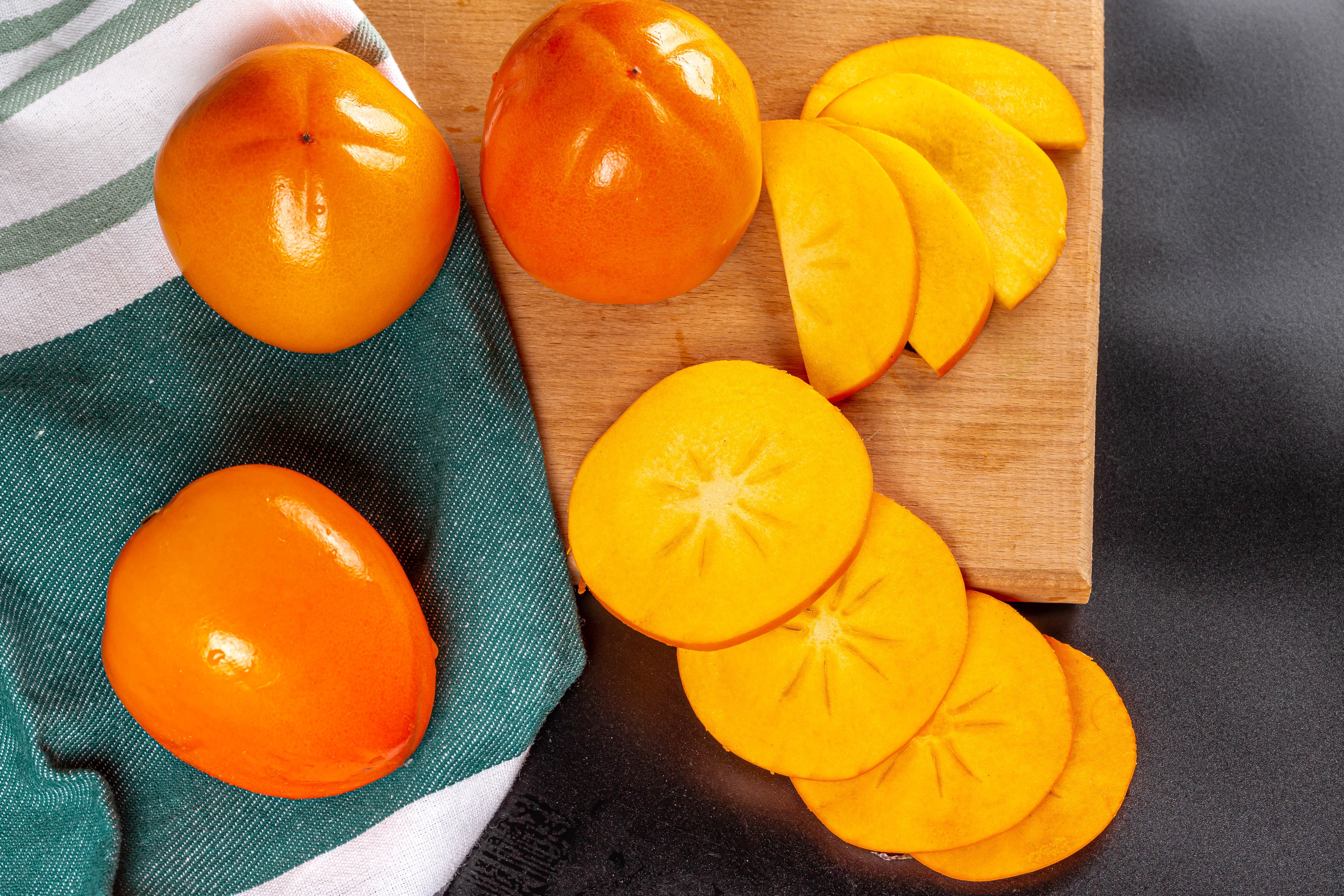 Persimmons on a cutting board with a towel HD Wallpaper