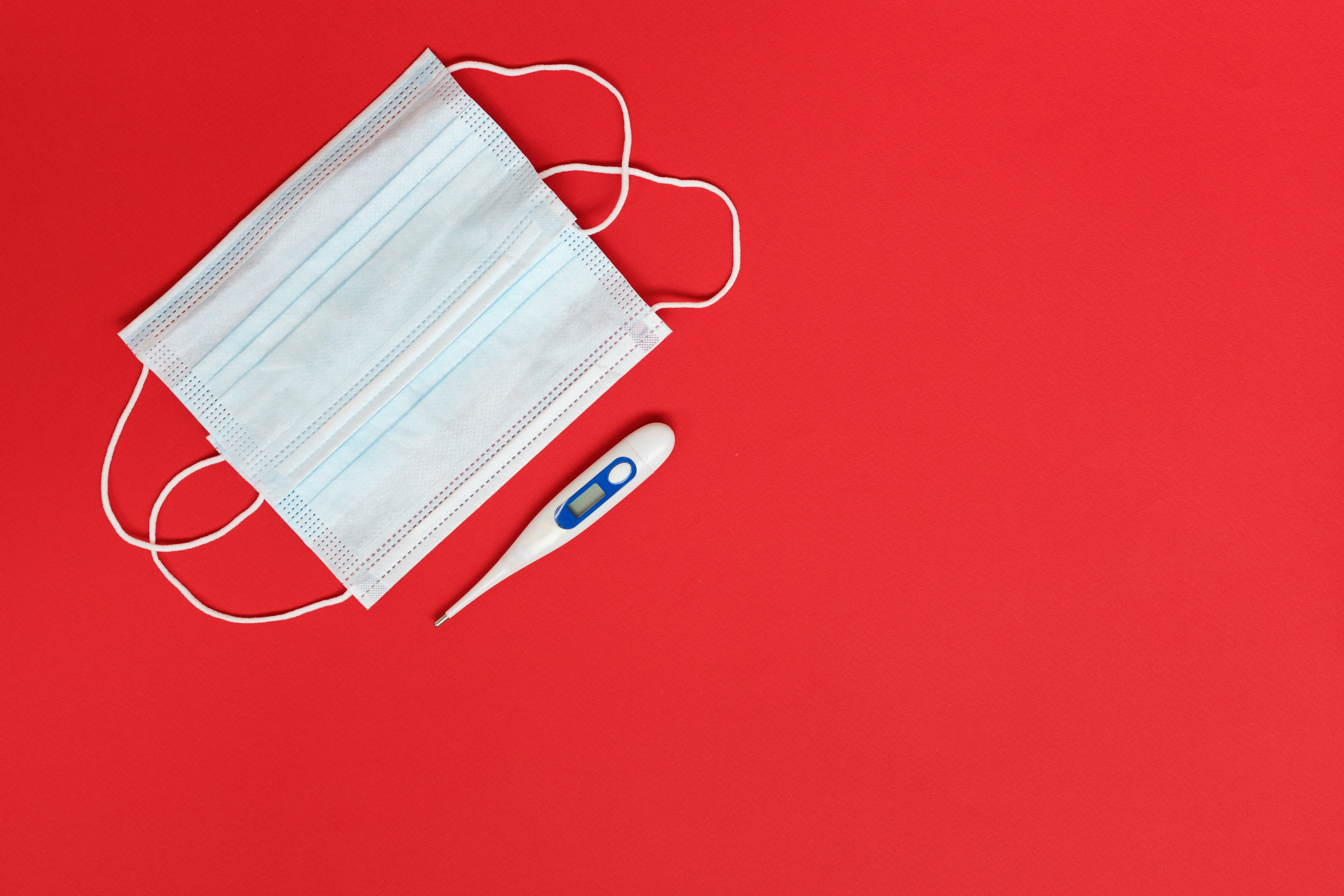 Face mask and thermometer on red background HD Wallpaper