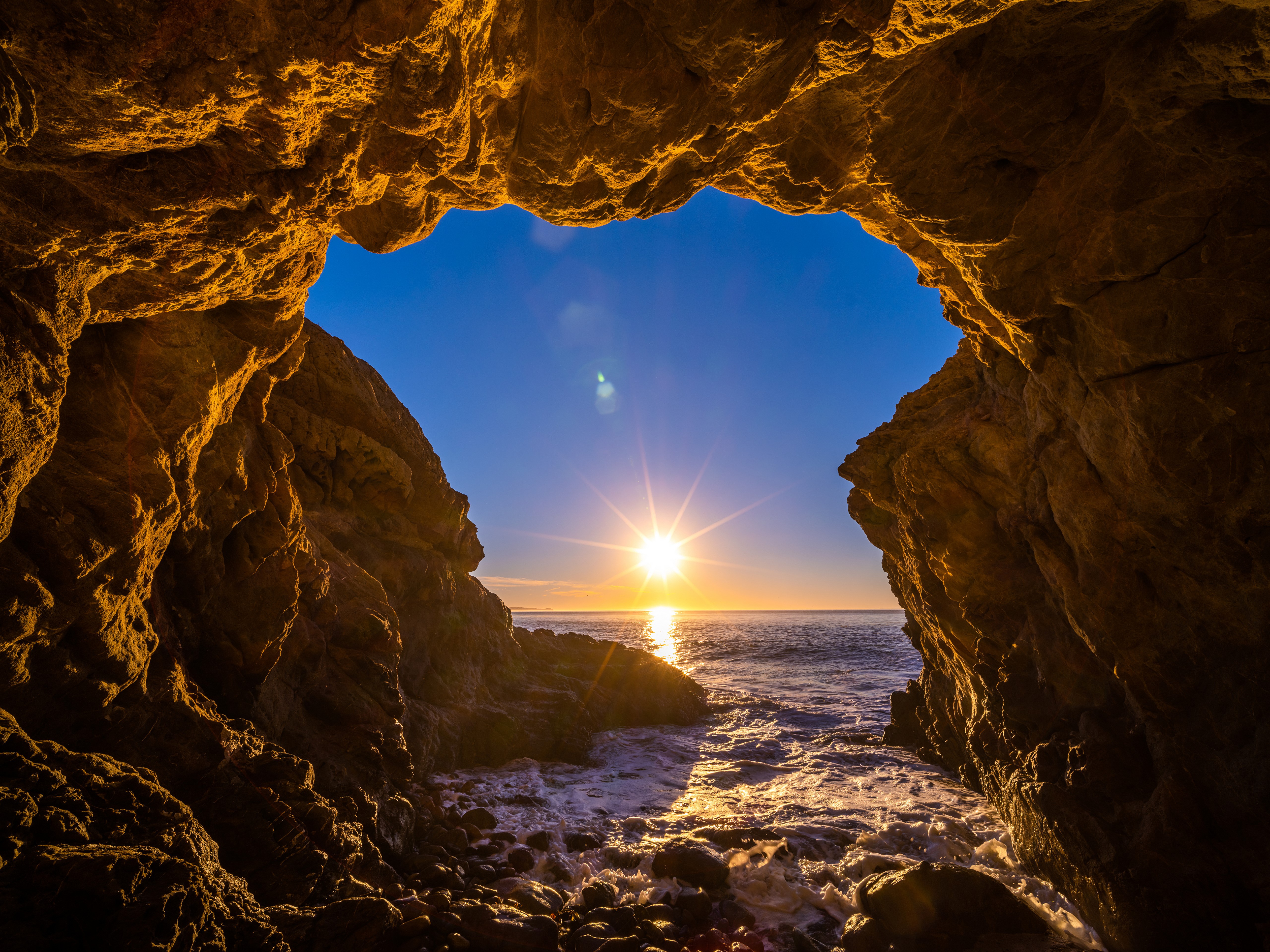 Cave entrance overlooking the ocean at sunset, El Matador Beach, California HD Wallpaper
