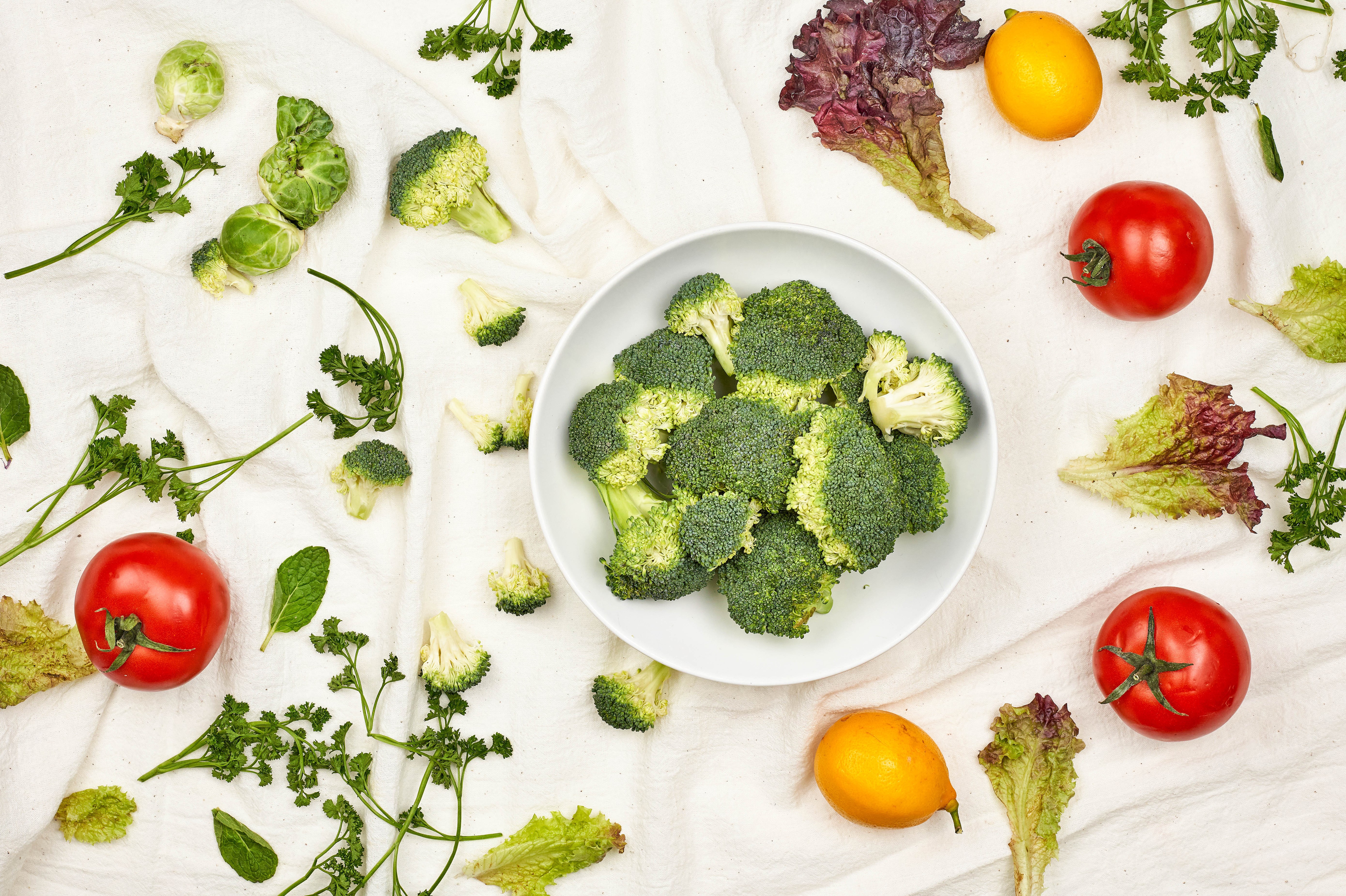 Broccoli, Tomatoes, Lemons, and Lettuce on a White Cloth HD Wallpaper