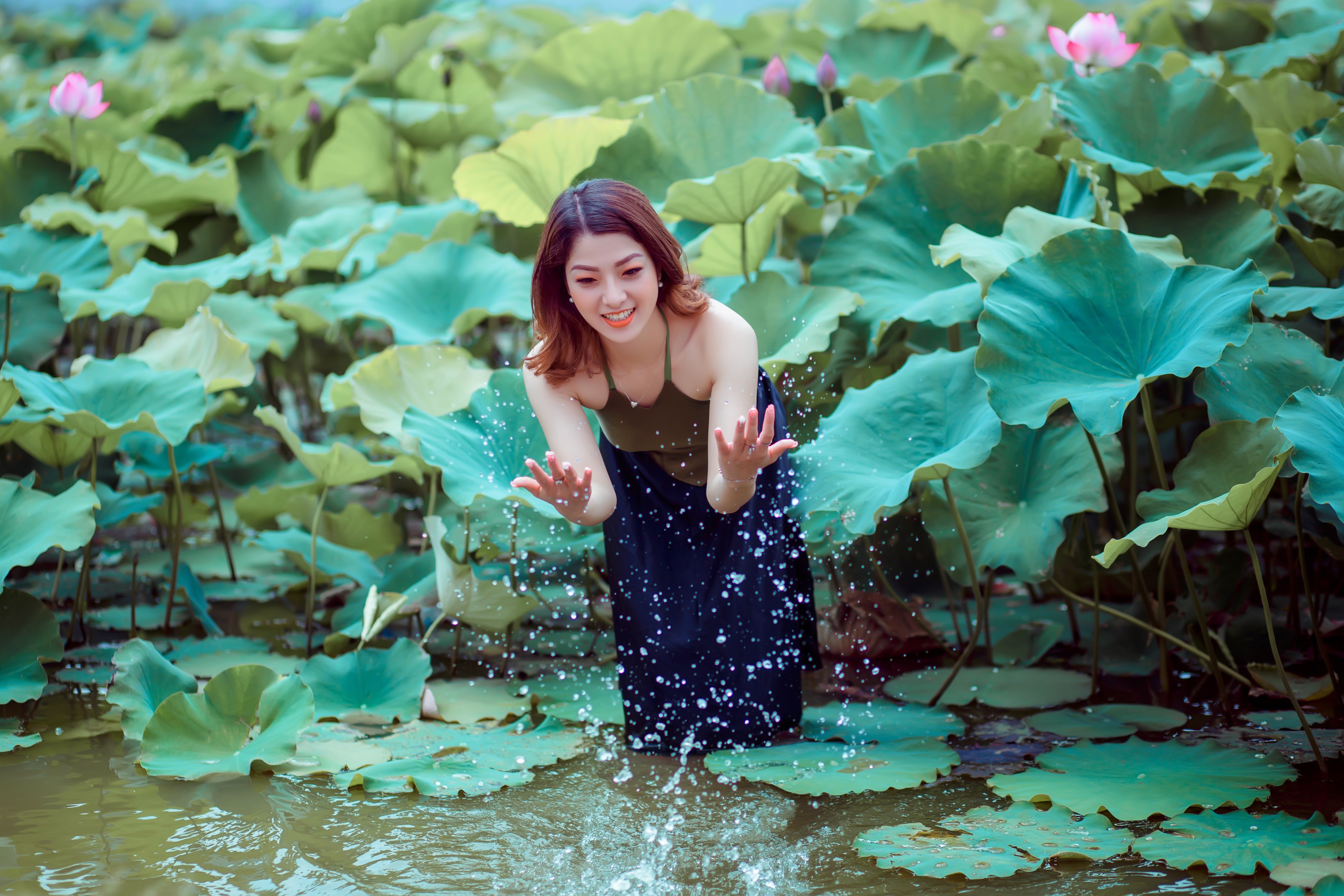 Woman splashing water in a lotus pond HD Wallpaper