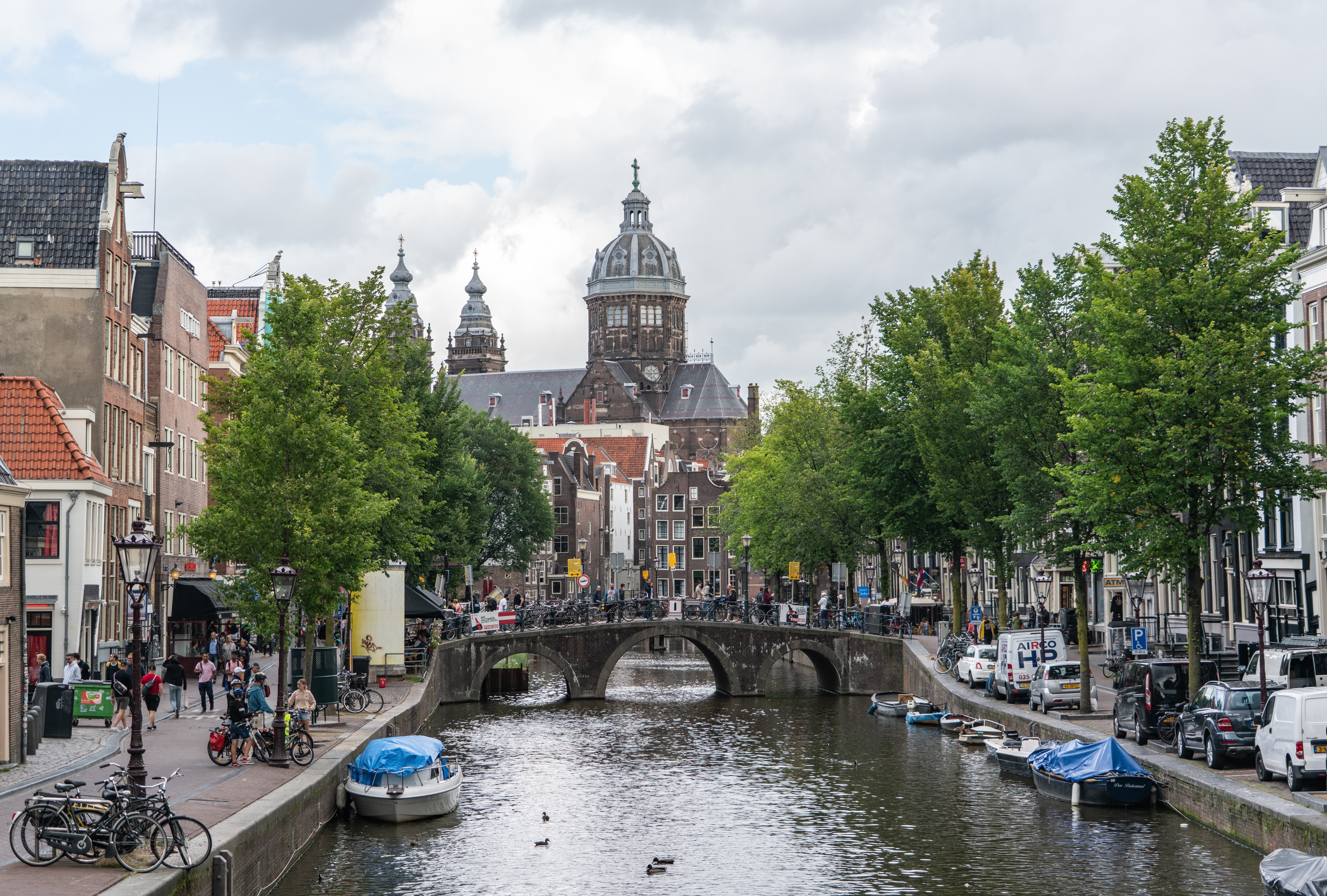 Amsterdam canal with bridges, boats, and trees HD Wallpaper