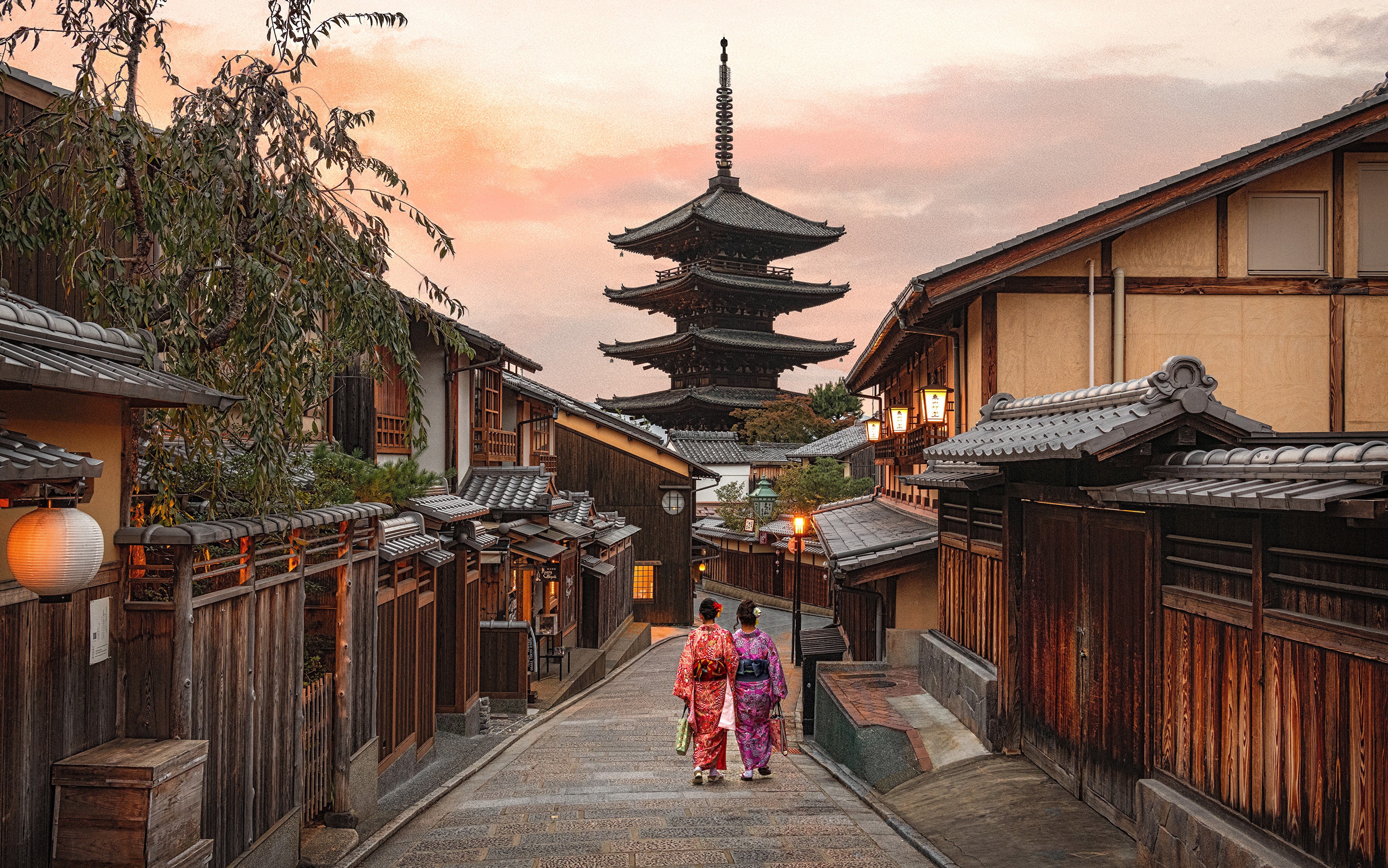 Two women in kimonos walk down a street in Kyoto, Japan towards a pagoda. HD Wallpaper