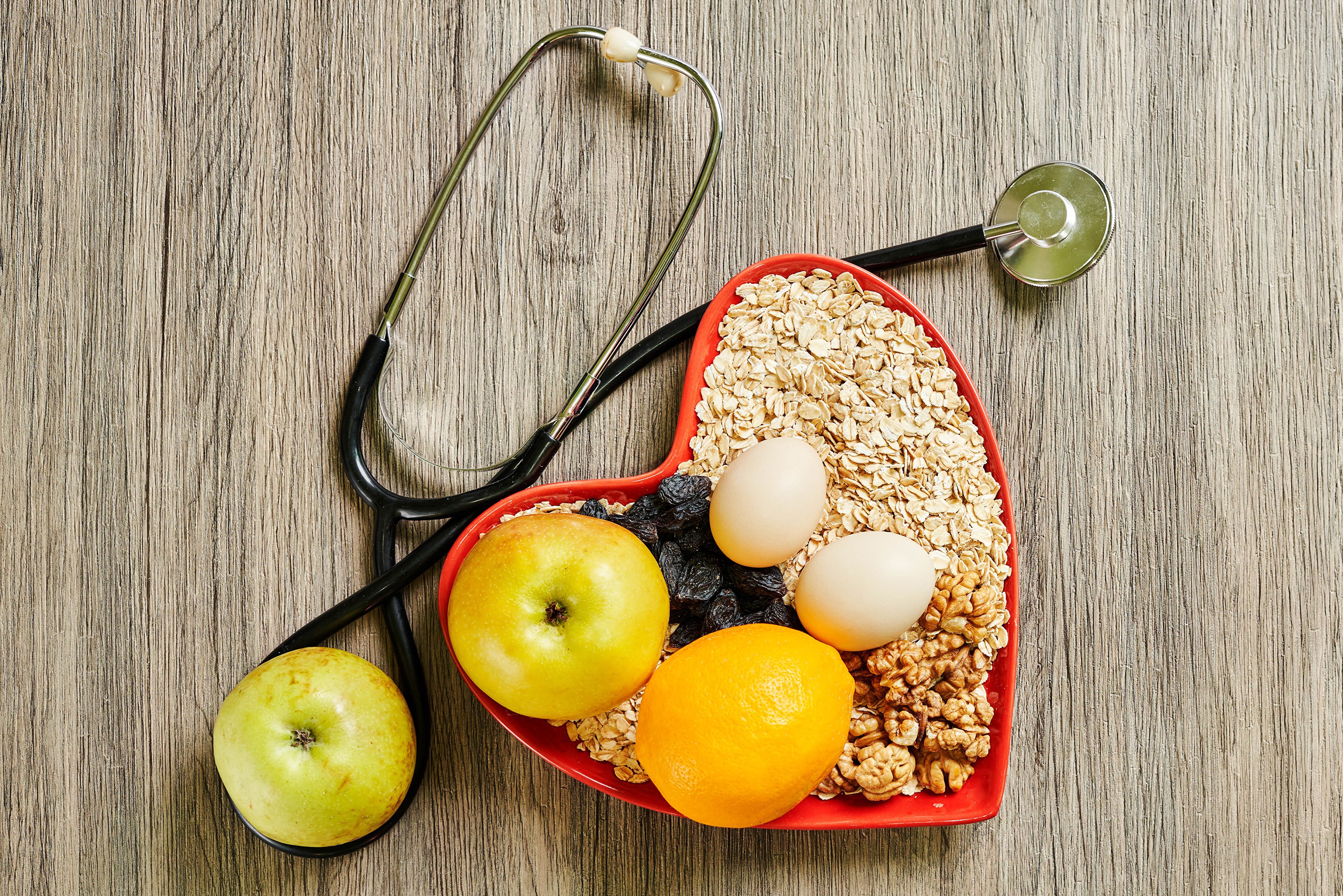 Heart-shaped bowl of oatmeal with fruits, eggs, nuts, and stethoscope HD Wallpaper
