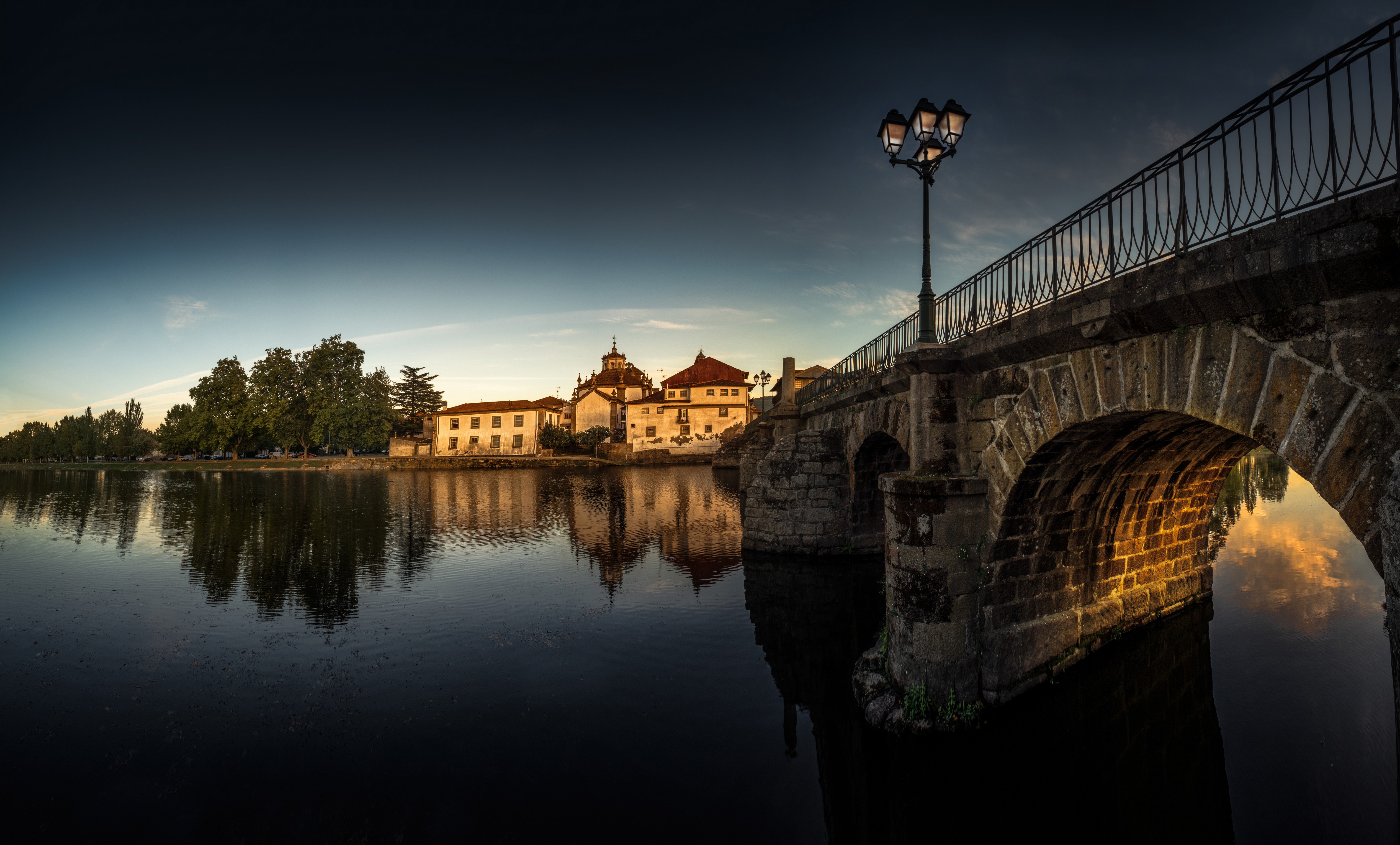 Stone bridge over river with buildings and street light in Portugal HD Wallpaper