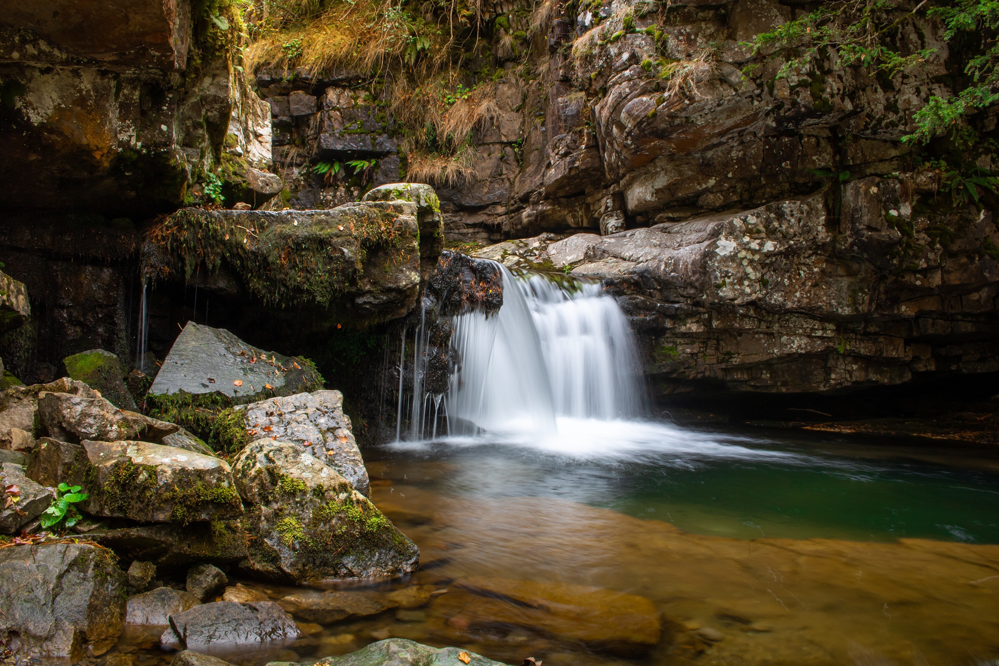 Waterfall cascading over mossy rocks HD Wallpaper