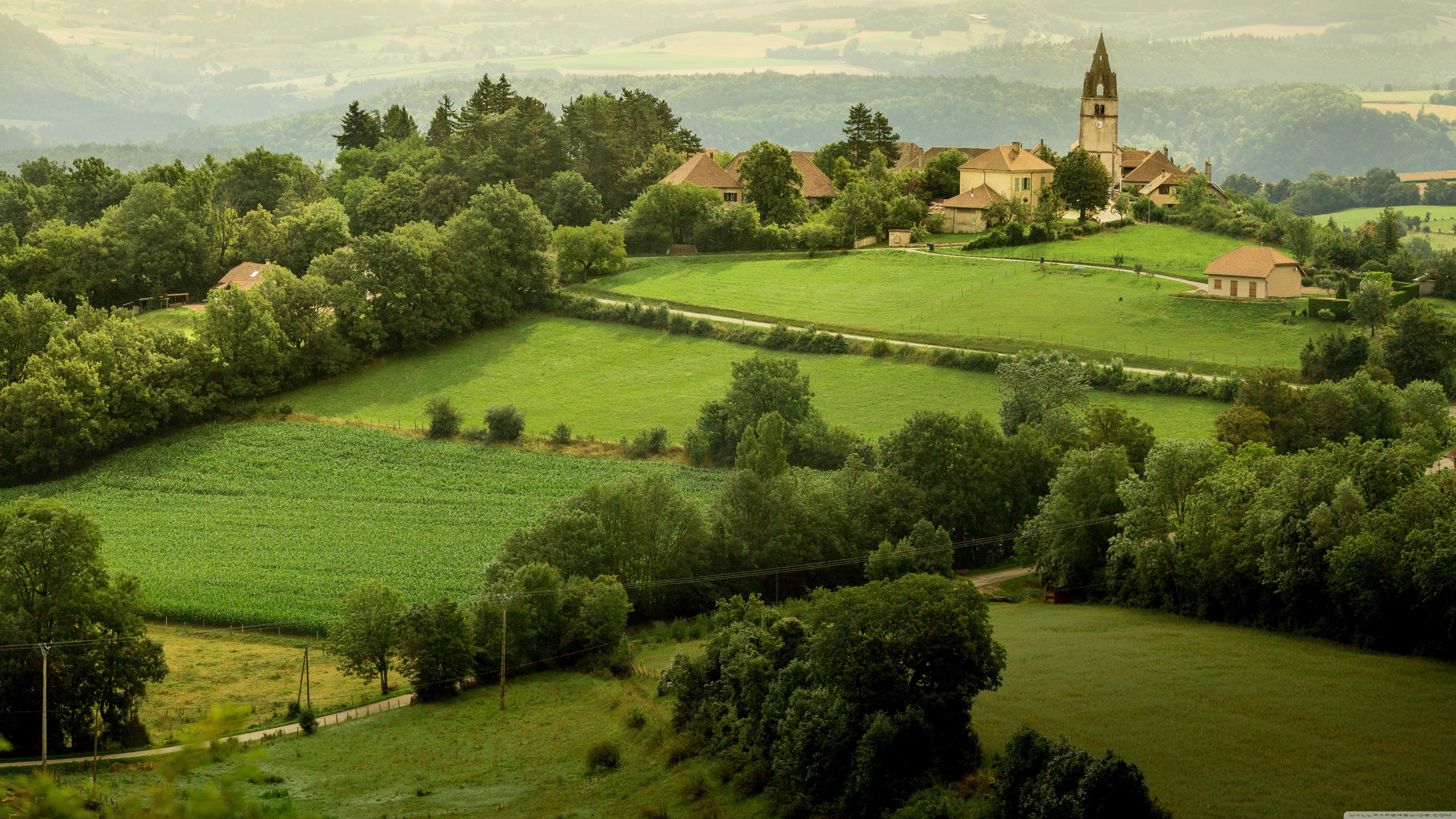 Village with church in green fields, France HD Wallpaper